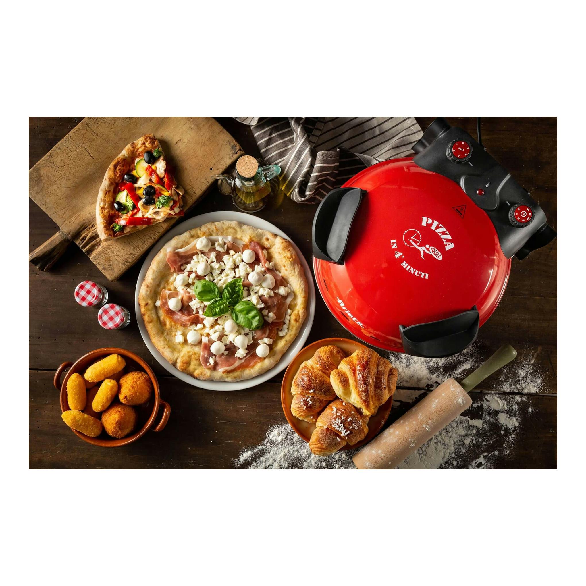 Horno para pizza Ariete rojo, vista cenital, con panel negro y controles, sobre mesa con pizzas y bollería.