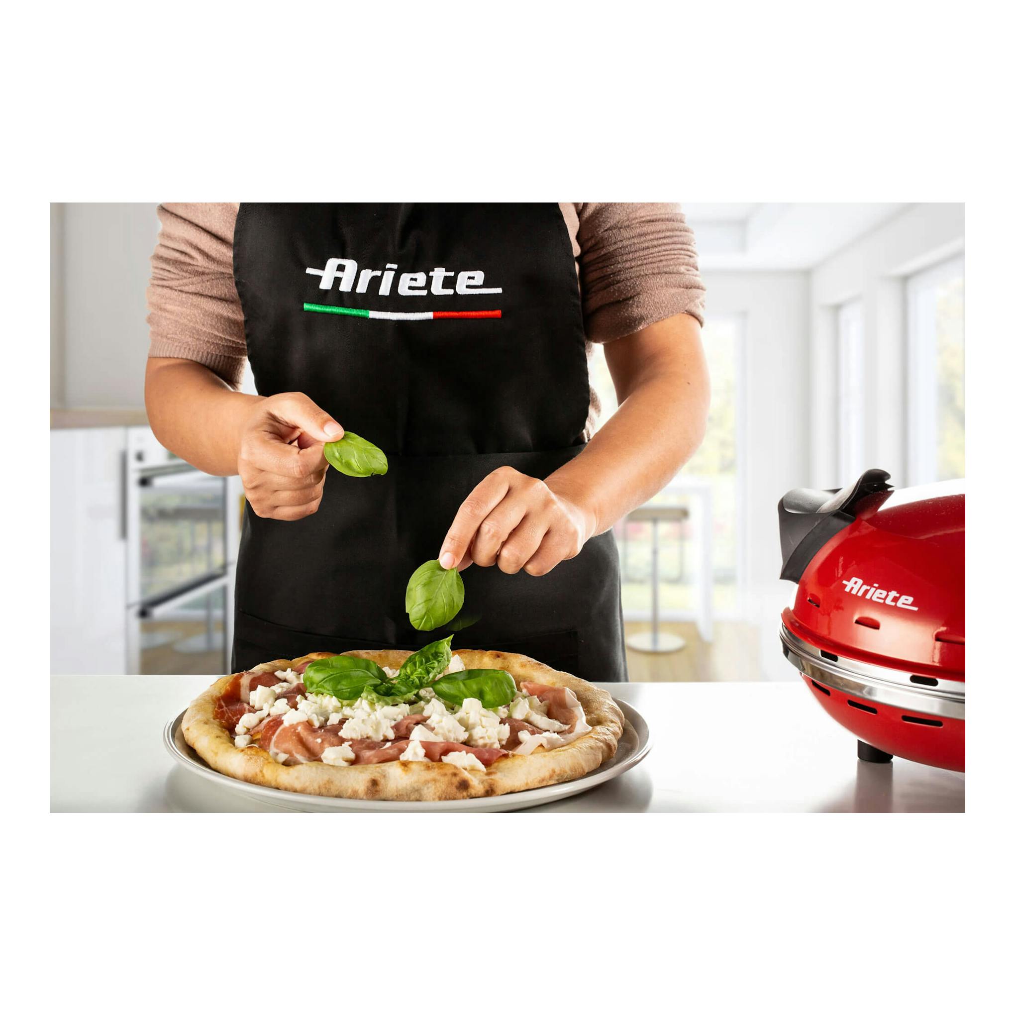 Mini horno para pizza Ariete rojo, vista lateral, con pizza en primer plano.