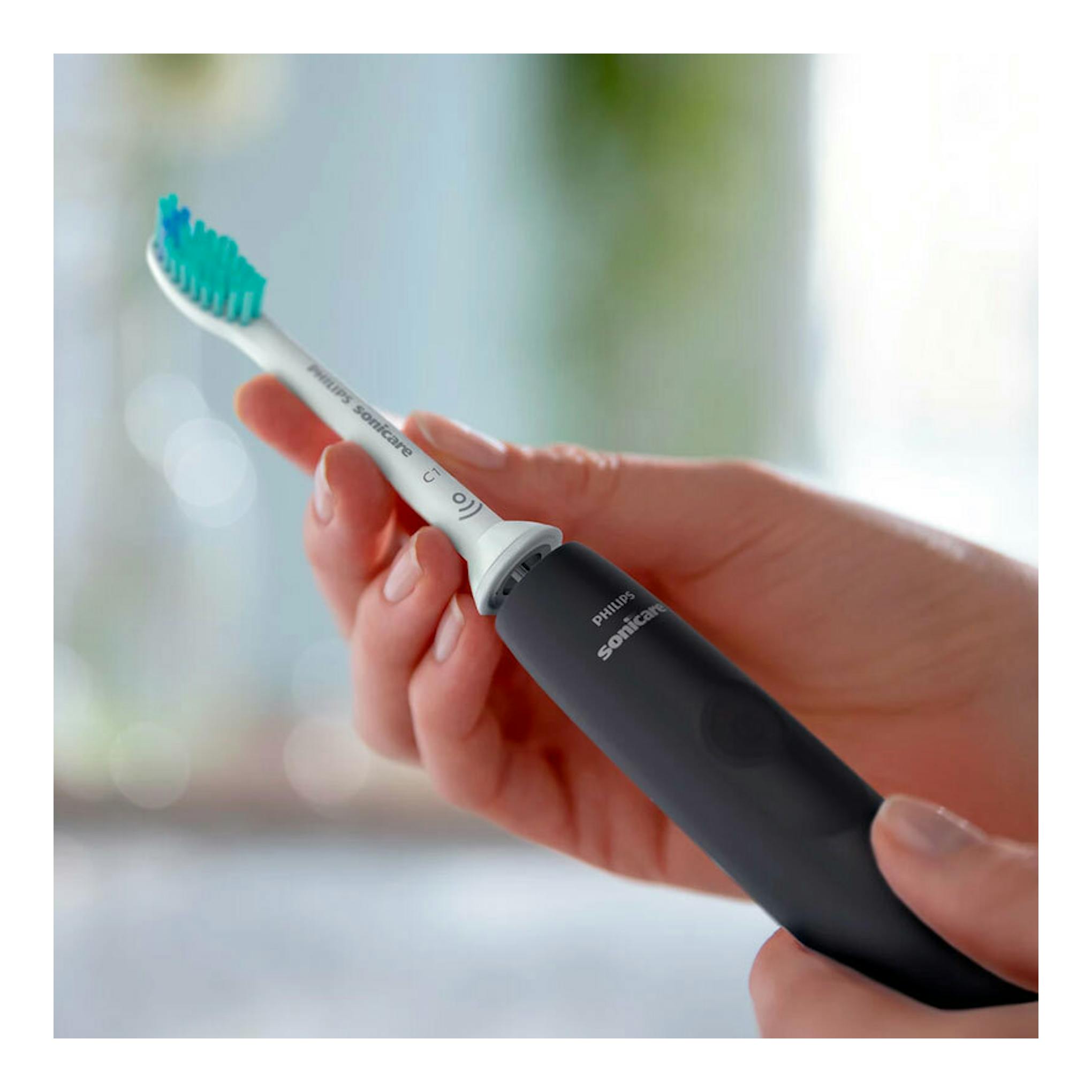Cepillo dental eléctrico Philips Sonicare HX3671/14 negro, sostenido con la mano, vista en primer plano.