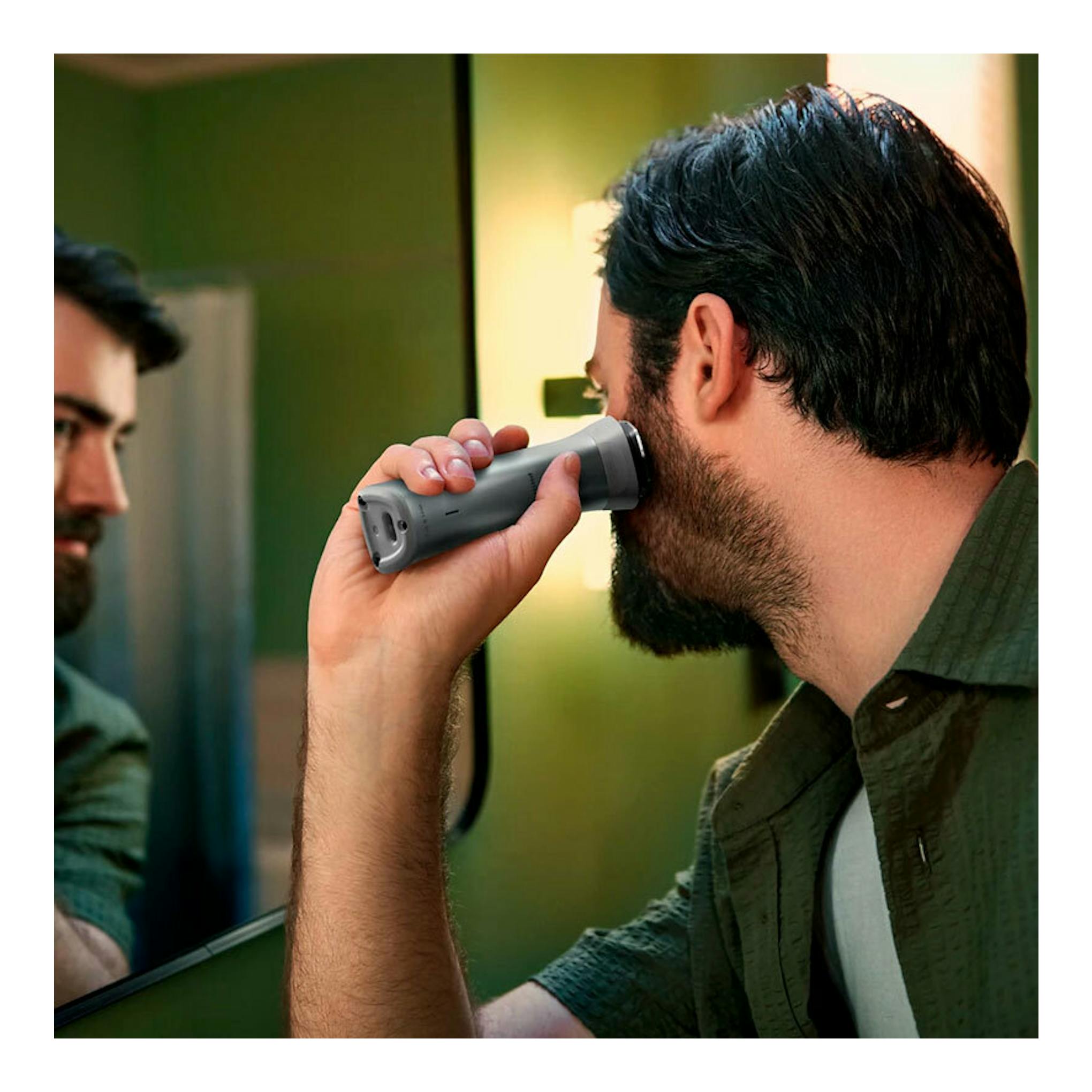 Cortapelos Philips MG5920/15 gris, en uso sobre la barba de un hombre frente al espejo.