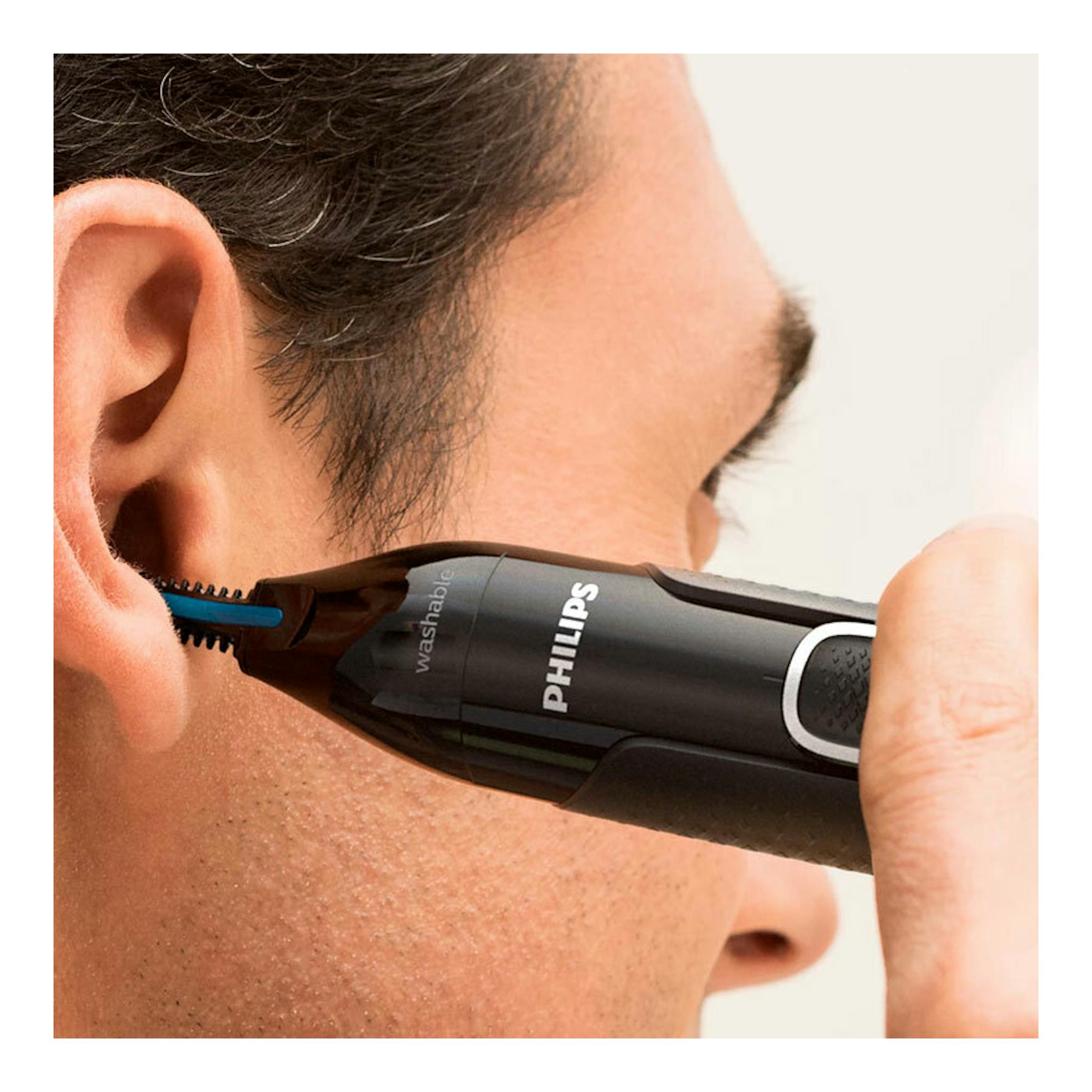 Cortapelos de nariz Philips NT5650/16 negro, en primer plano junto a la oreja de un hombre.
