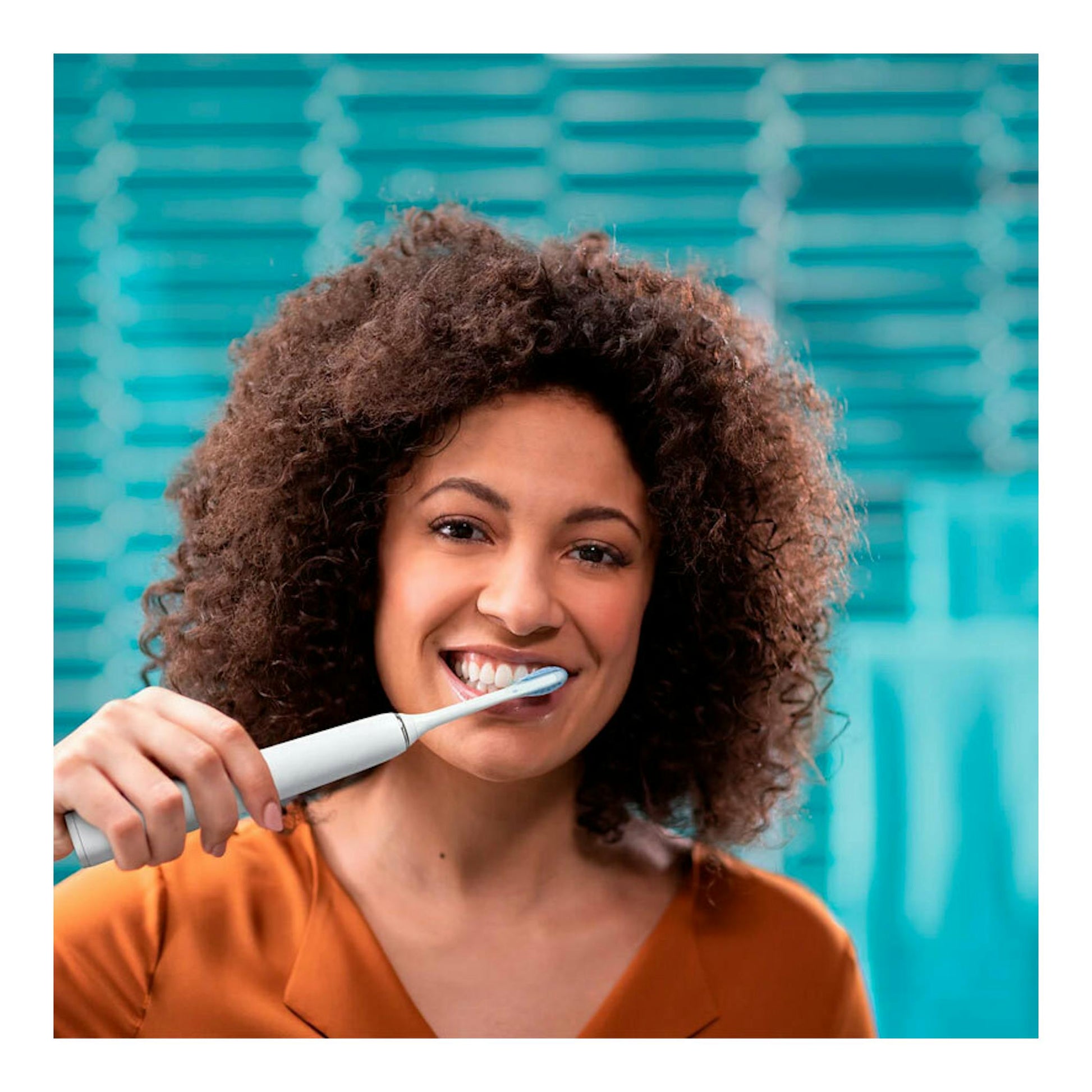 Mujer sonriendo cepillándose los dientes con cepillo dental eléctrico Philips HX9913/17, vista frontal.