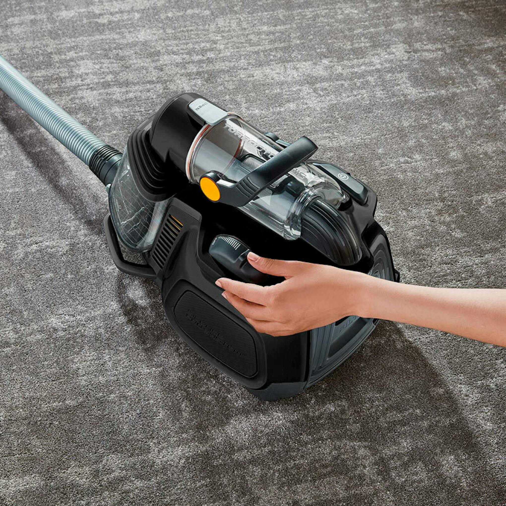 Aspiradora trineo AEG LX7-2-EB-P sin bolsa sobre una alfombra, con una mano sujetando el asa