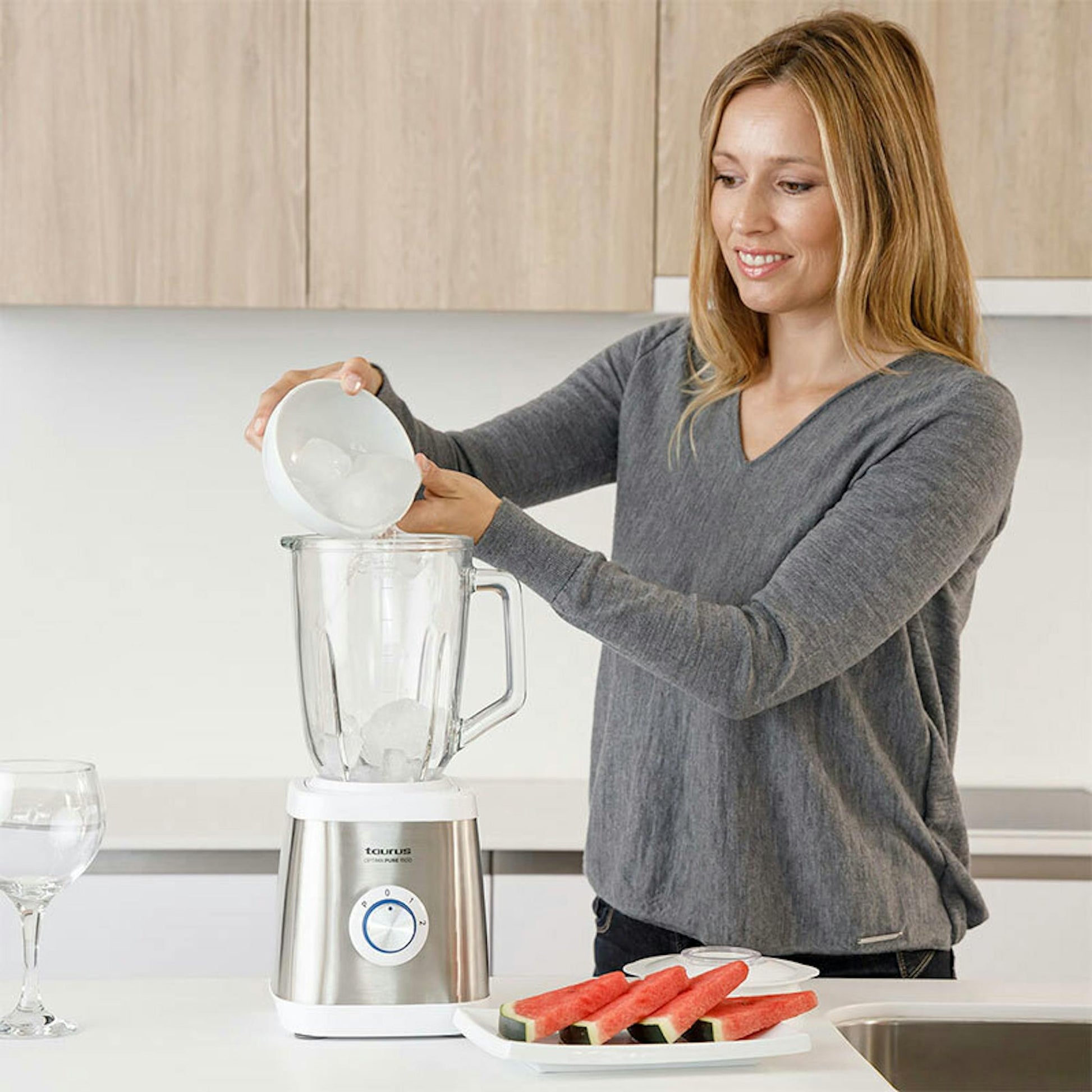 Batidora de vaso Taurus Optima Pure 1500 con una mujer añadiendo hielo en la jarra en una cocina