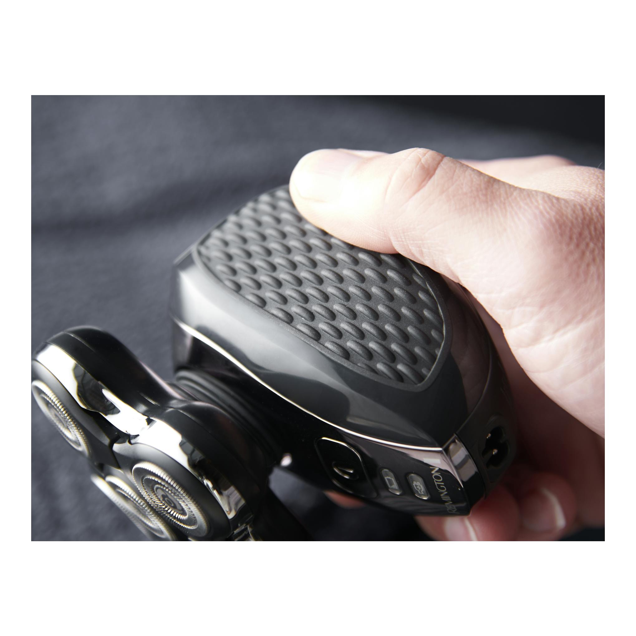 Afeitadora Remington Ultimate Series RX5 XR1500 negra, en primer plano, sostenida con la mano; cabezales visibles.