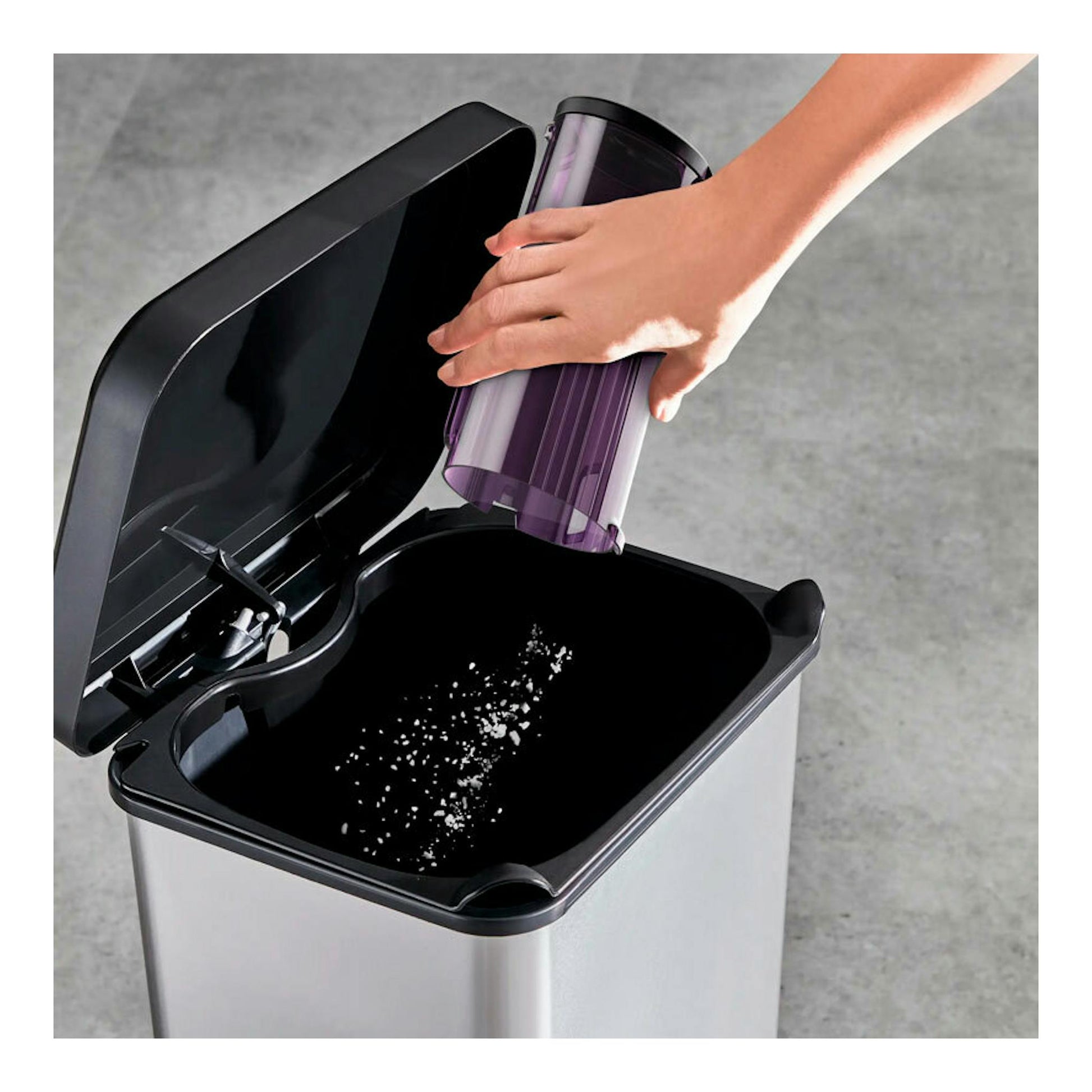 Depósito morado de aspirador Rowenta RH2077WO vaciándose en una papelera negra, vista superior oblicua.