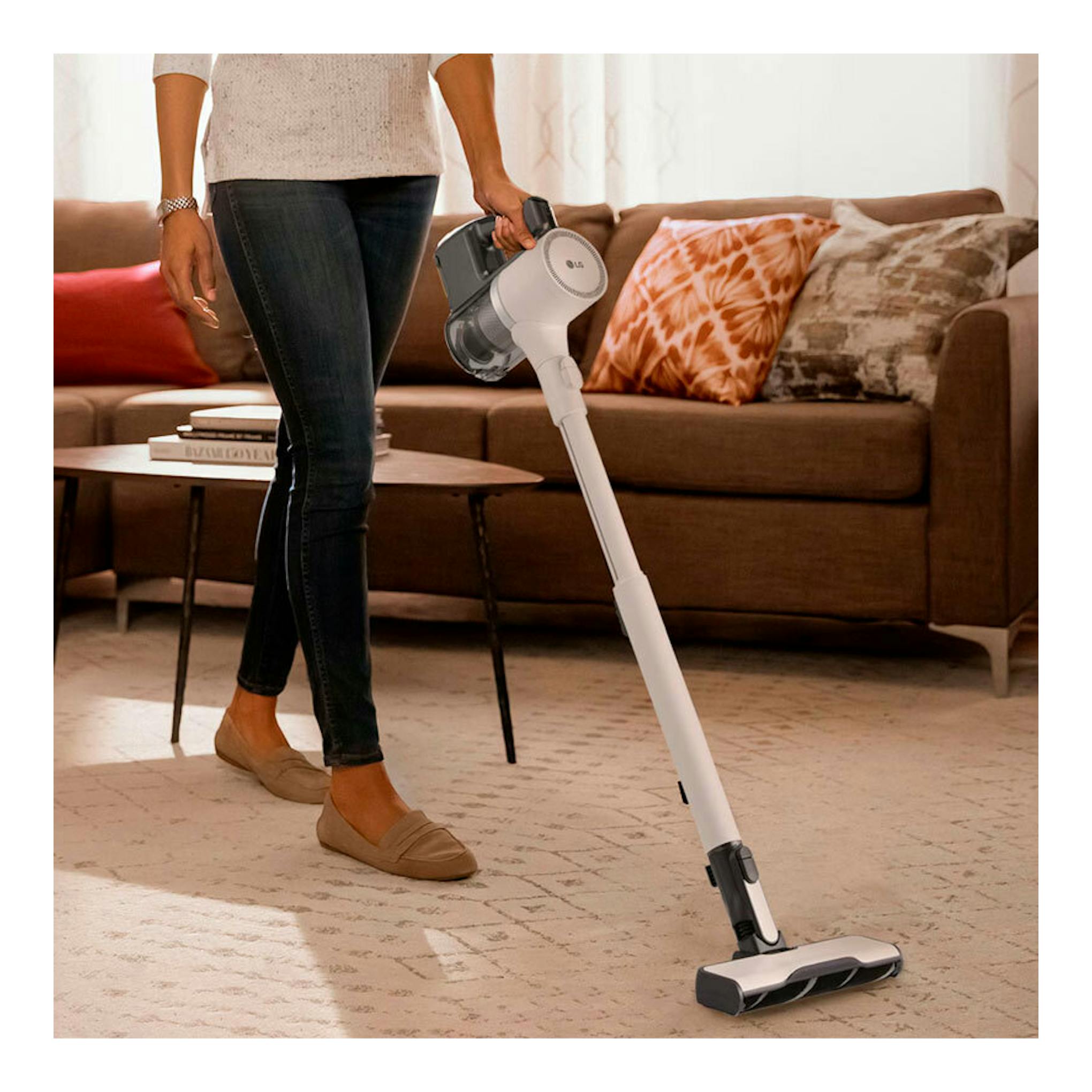 Aspirador escoba LG A9K-LITE1C blanco en uso en un salón, junto a un sofá.