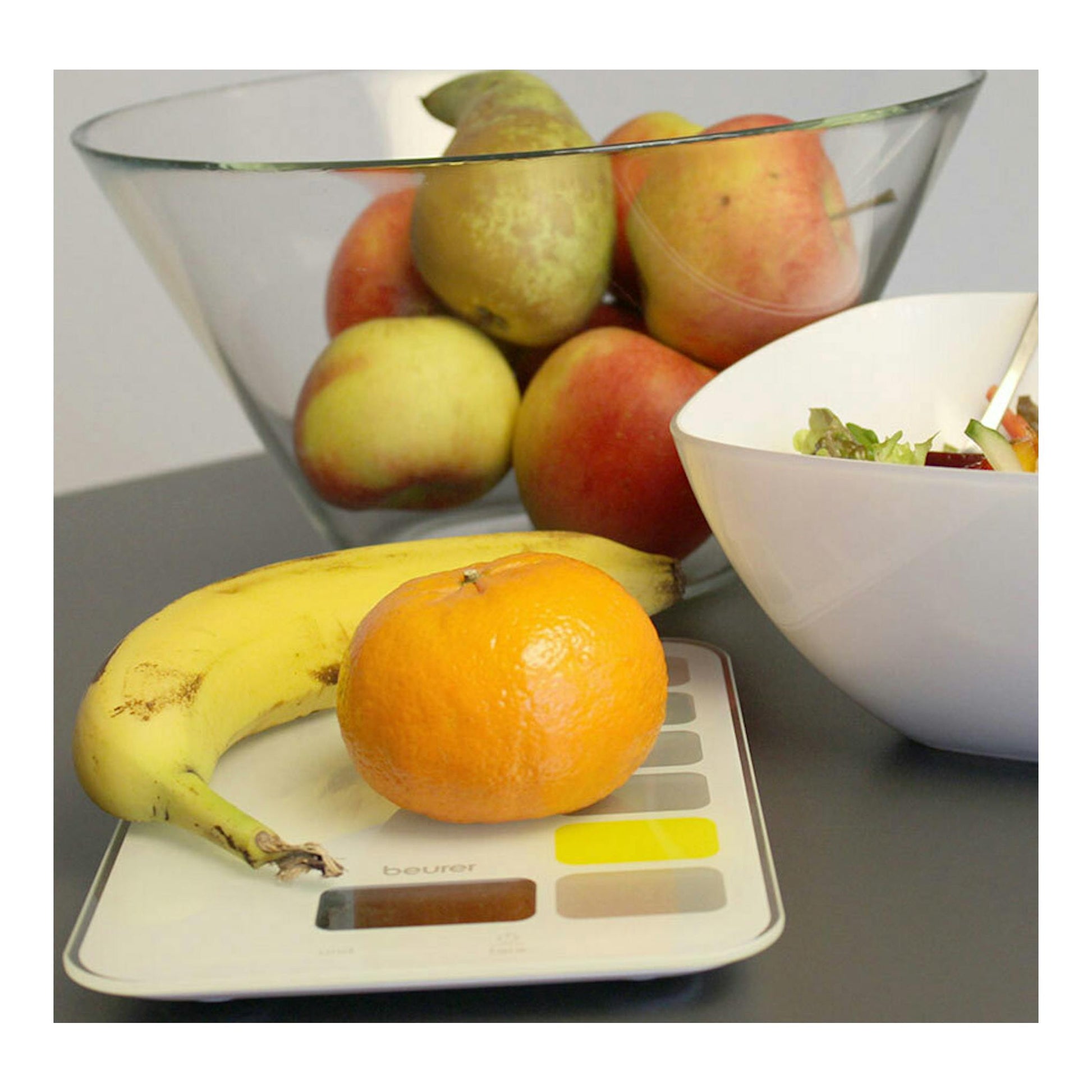 Balanza de cocina Beurer KS-19 Sequence blanca, vista frontal, con fruta sobre la superficie.