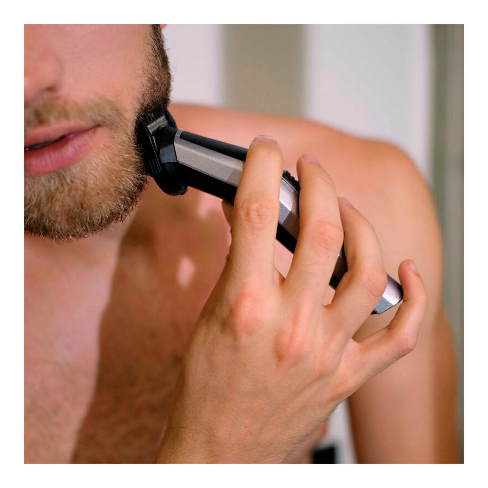 Recortadora Babyliss MT725E negra y plateada, en primer plano, usada en la barba de un hombre.