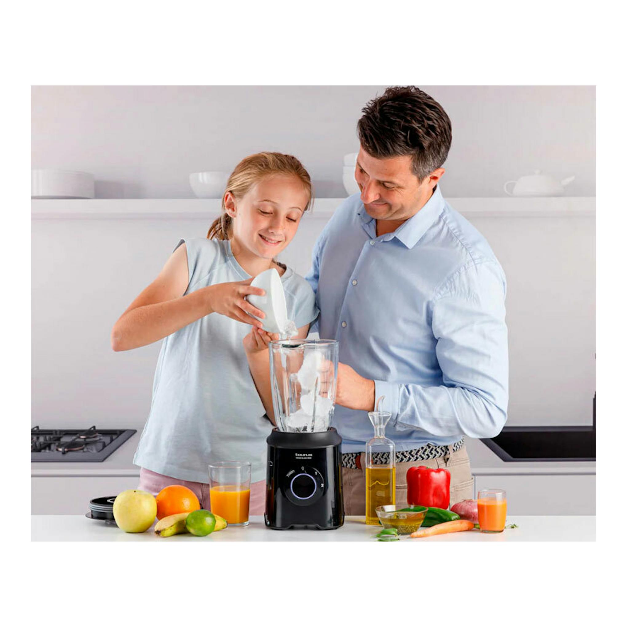 Batidora de vaso Taurus Prior Glass 1500 negra sobre encimera, con una niña y un hombre preparando fruta.