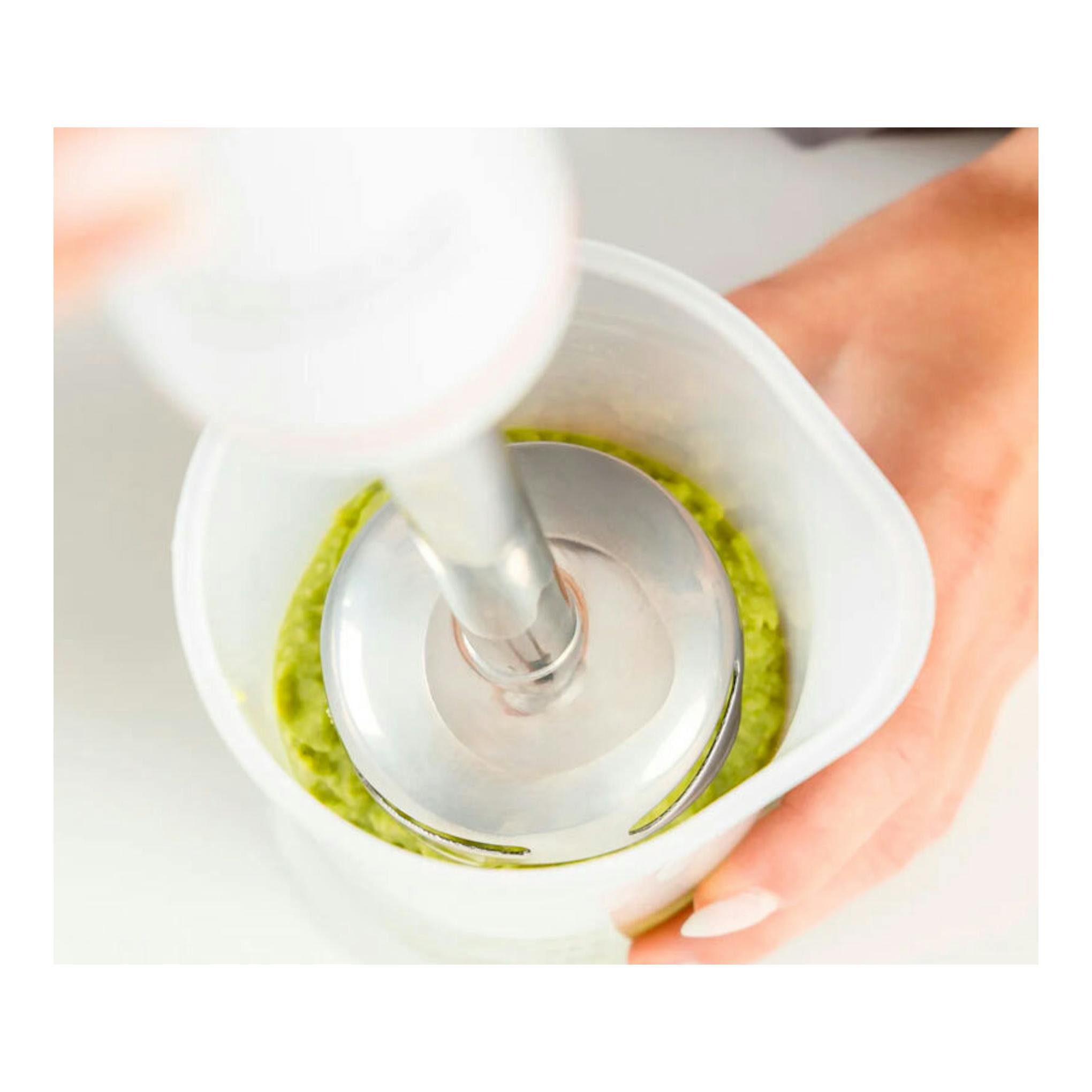 Batidora de mano Taurus Robot 1000 Inox, vista superior, triturando salsa verde en un vaso blanco.