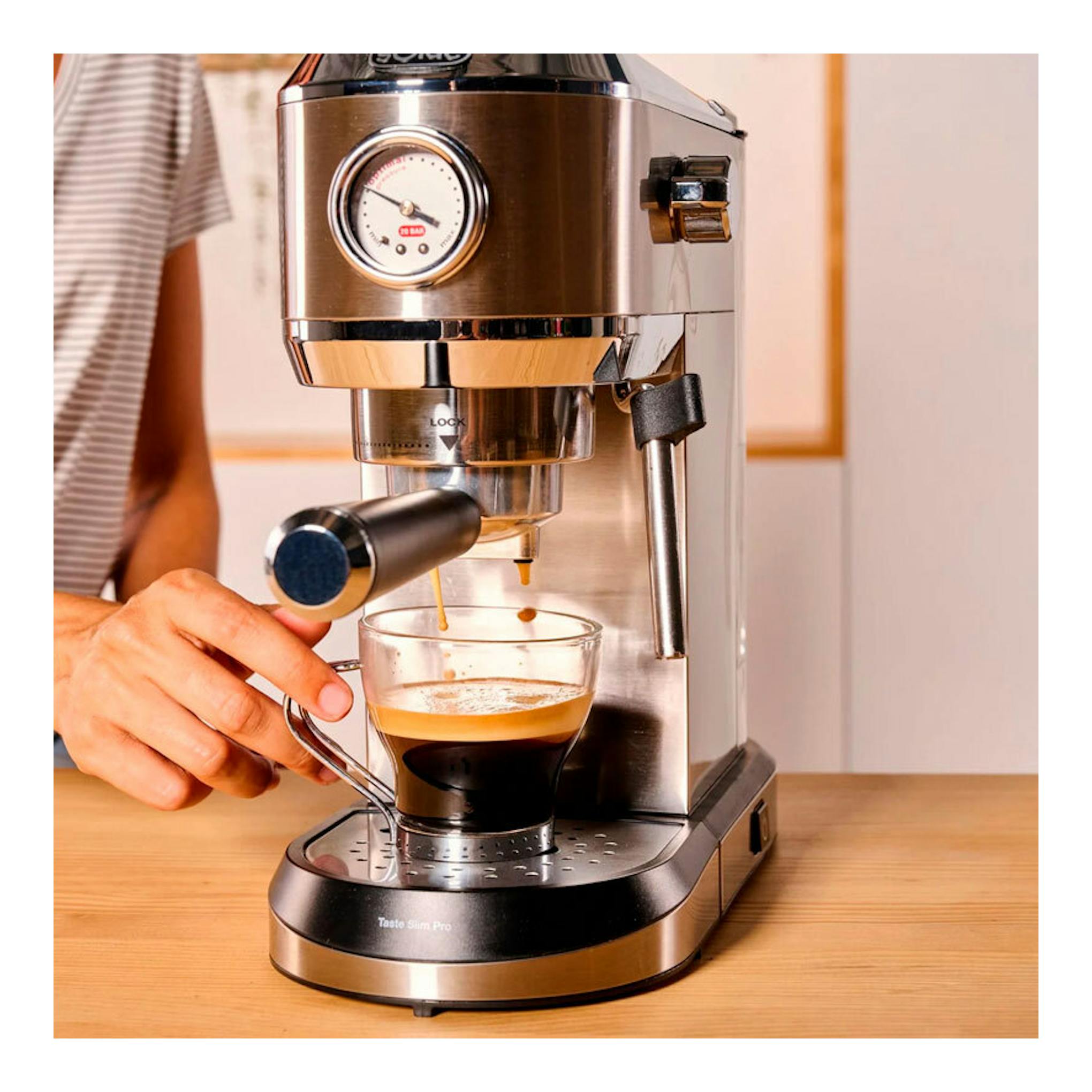 Cafetera espresso Solac CE4520 de acero inoxidable, vista frontal, con taza bajo el grupo y una mano sujetándola.