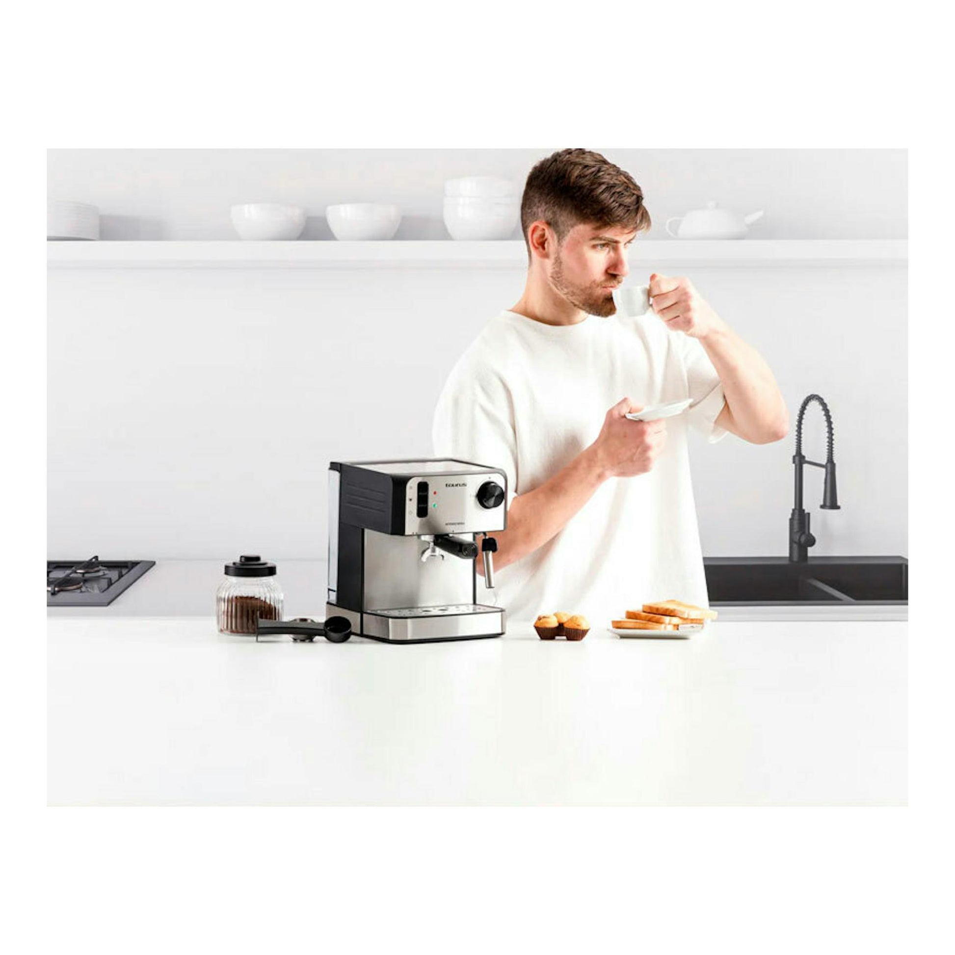Cafetera espresso Taurus Intenso Moka de acero inoxidable y negro sobre encimera, junto a un hombre con taza.