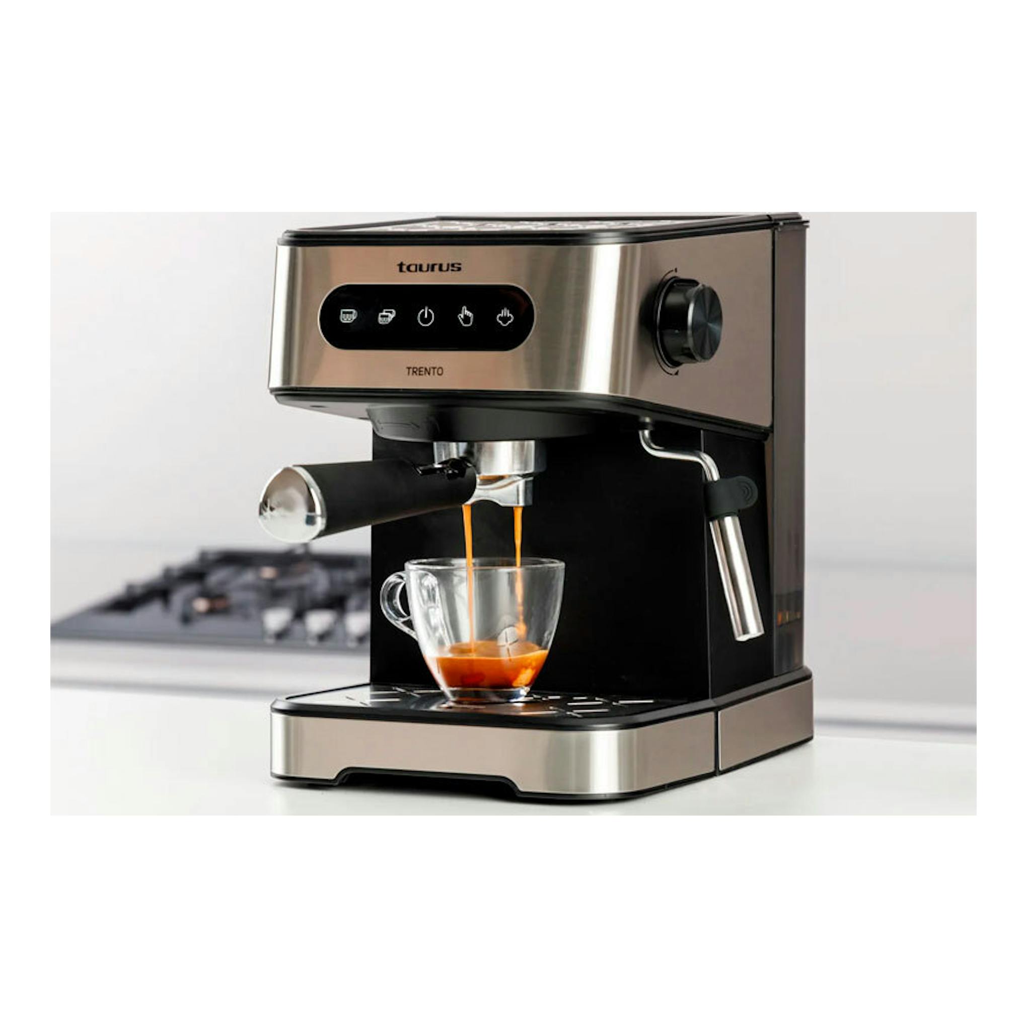 Cafetera espresso Taurus Trento negra y acero inoxidable, vista frontal, sirviendo café en una taza de vidrio.