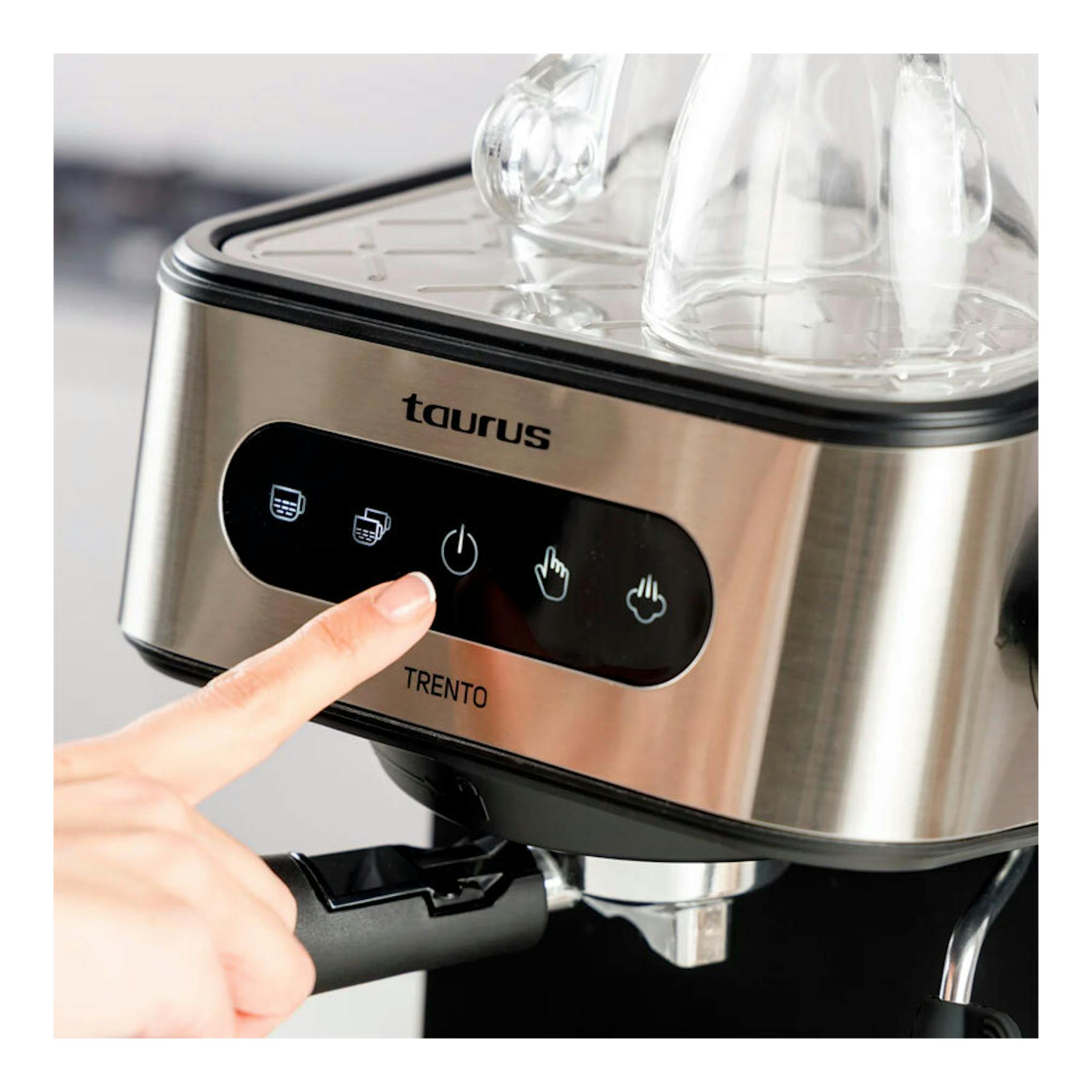 Vista frontal en primer plano de cafetera espresso Taurus Trento de acero inoxidable, con un dedo pulsando el panel.