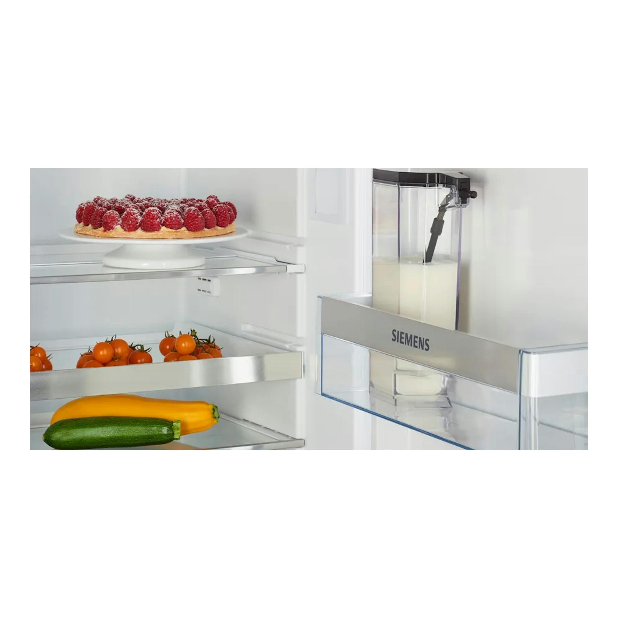 Interior de frigorífico con depósito de leche Siemens en la puerta, vista frontal, junto a frutas y verduras.