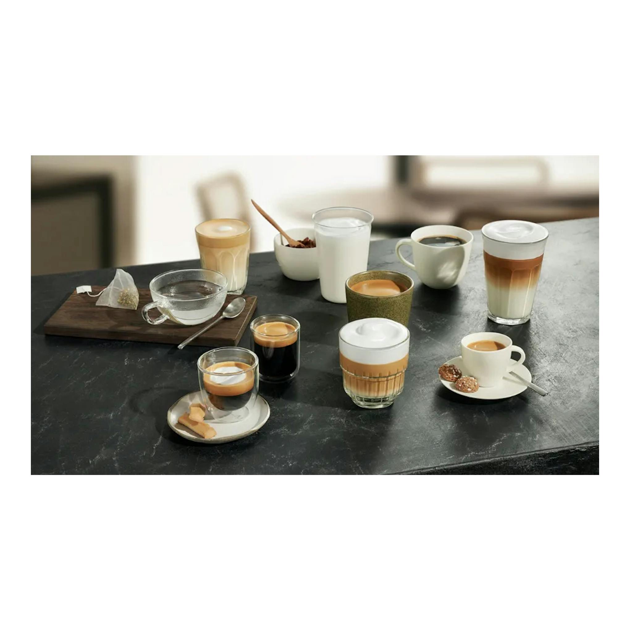 Varias tazas y vasos con café sobre una mesa negra, vista frontal.