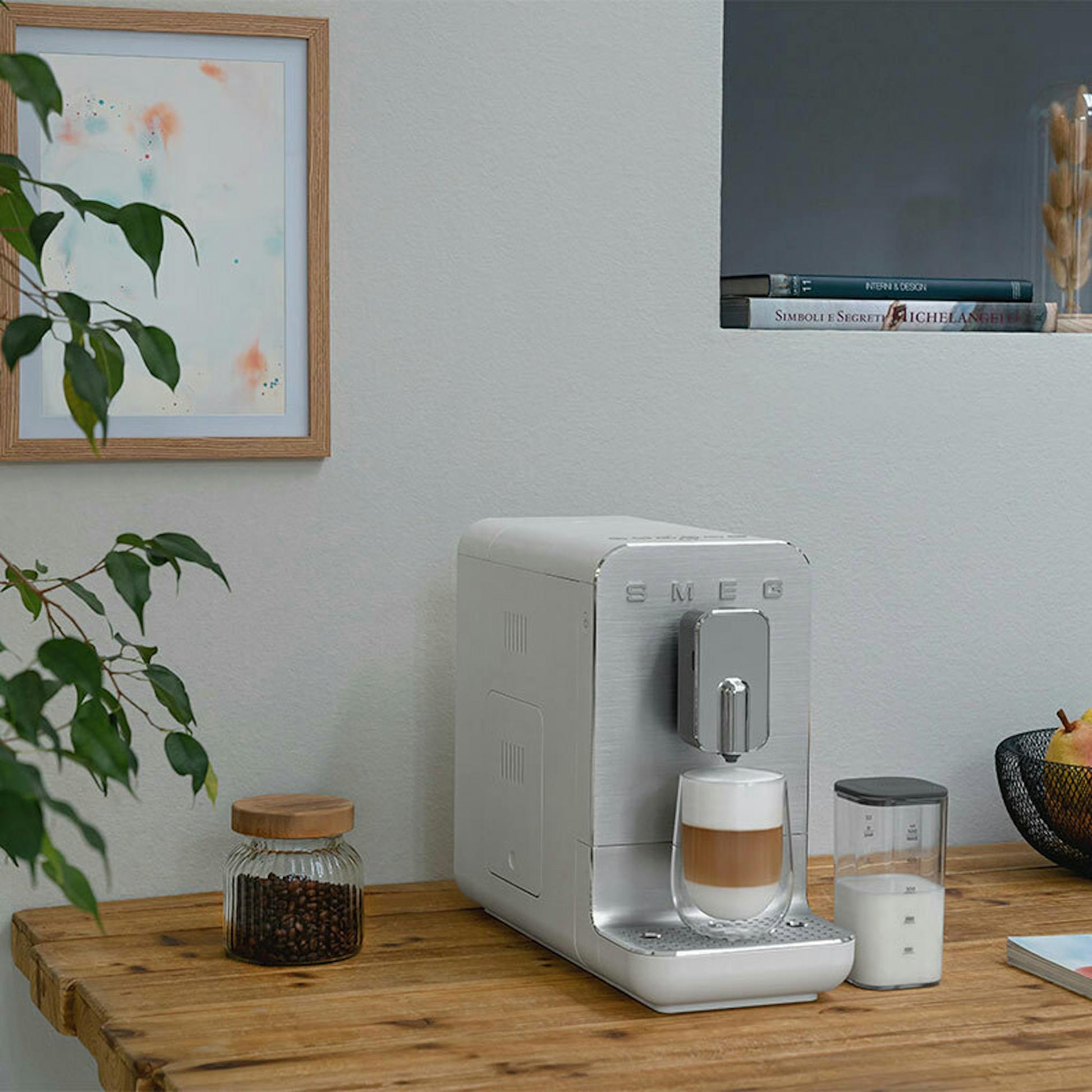 Cafetera superautomática Smeg BCC13WHMEU blanca sobre una mesa de madera
