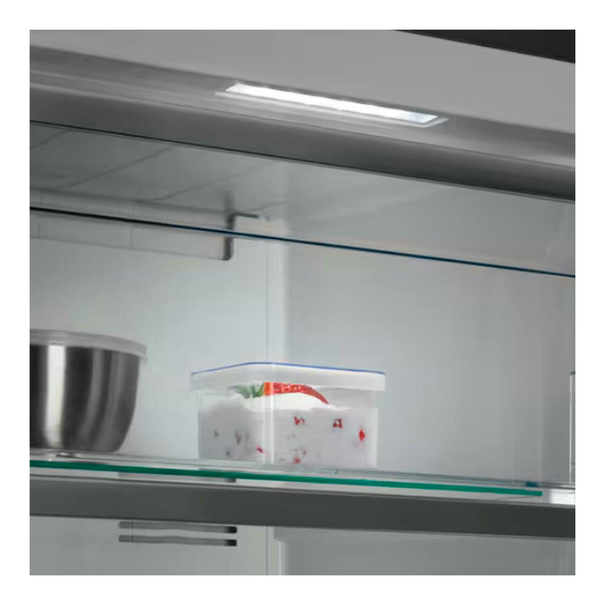 Interior de congelador blanco AEG OAG7M281EW, con estante de vidrio, bol metálico y recipiente plástico.