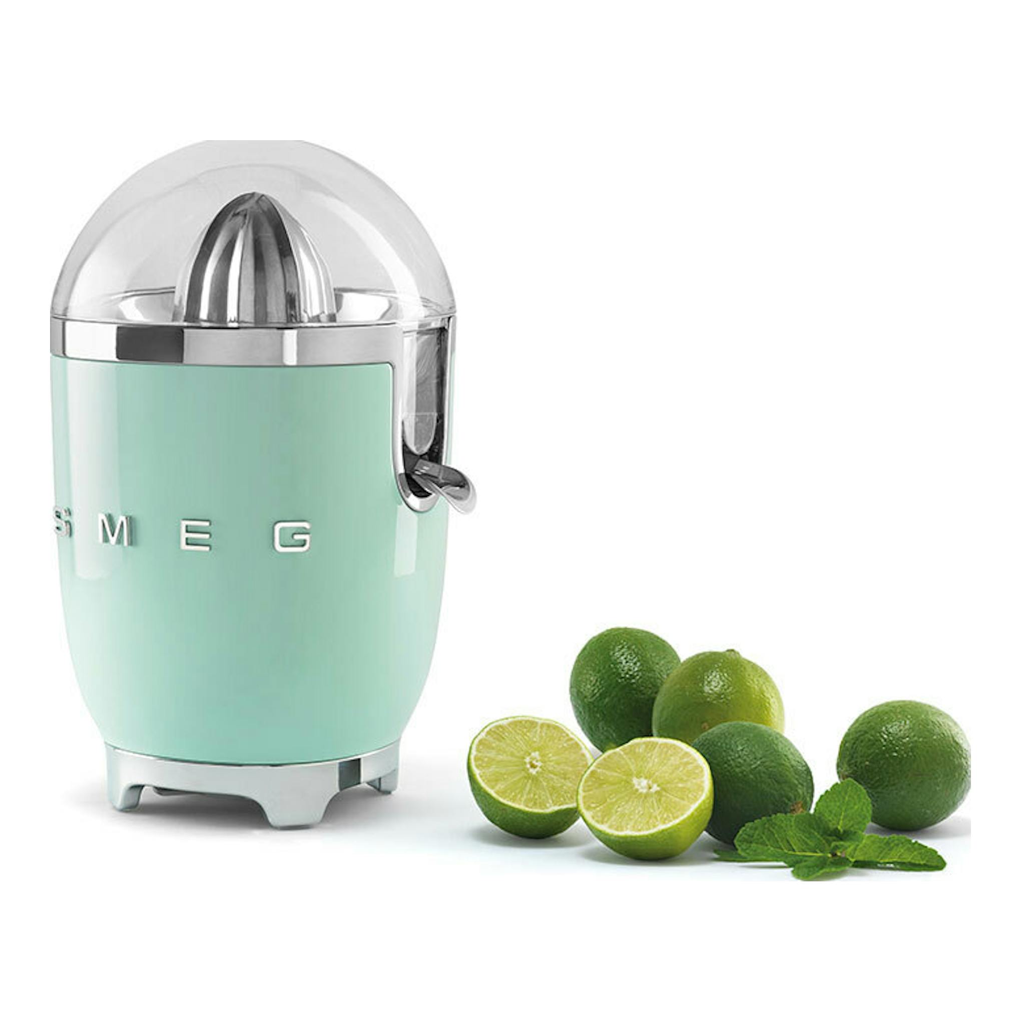 Exprimidor Smeg CJF11PGEU verde menta, vista frontal tres cuartos, junto a limas enteras y partidas.