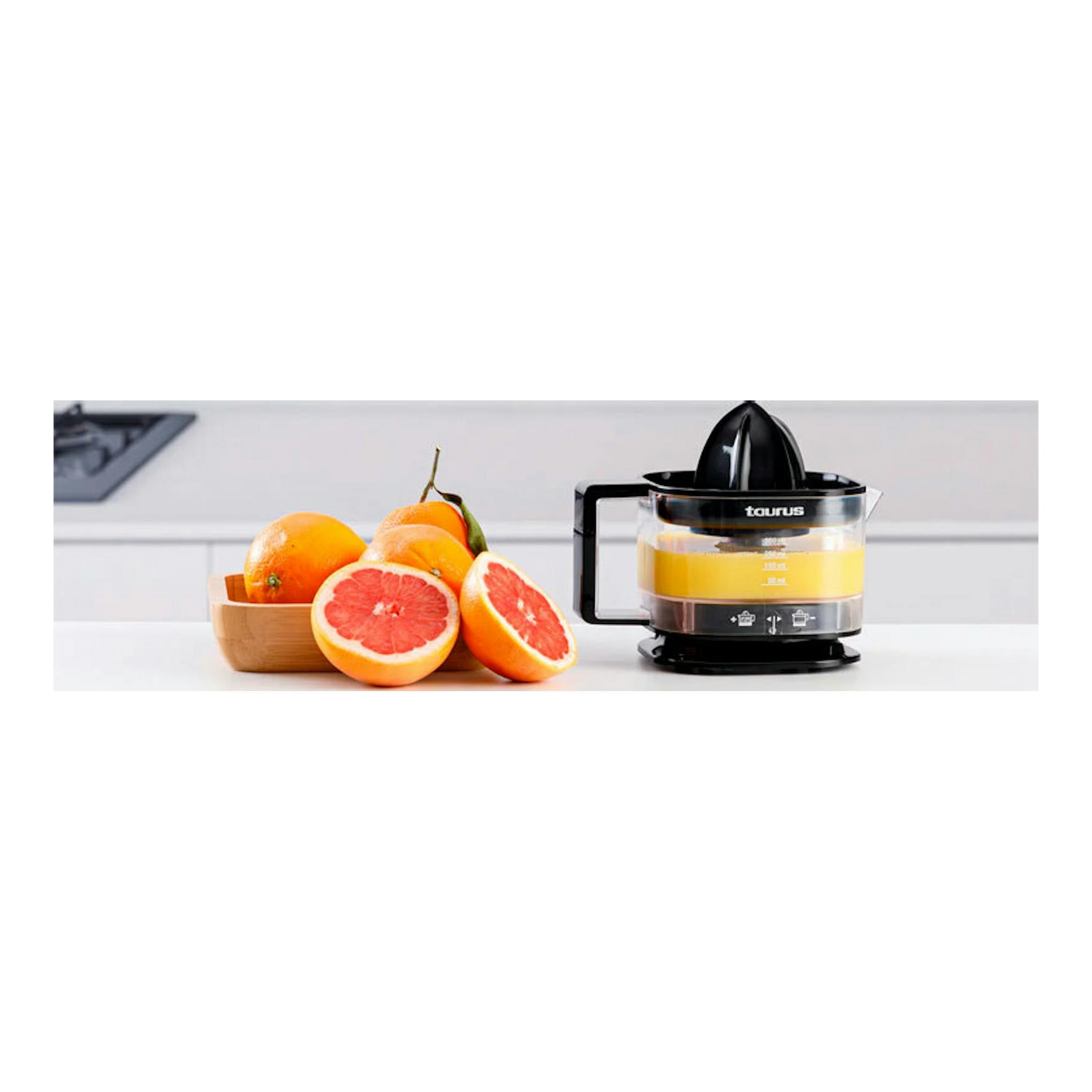 Exprimidor Taurus TC-350 Nero negro, vista frontal, junto a naranjas y pomelos sobre una encimera blanca.