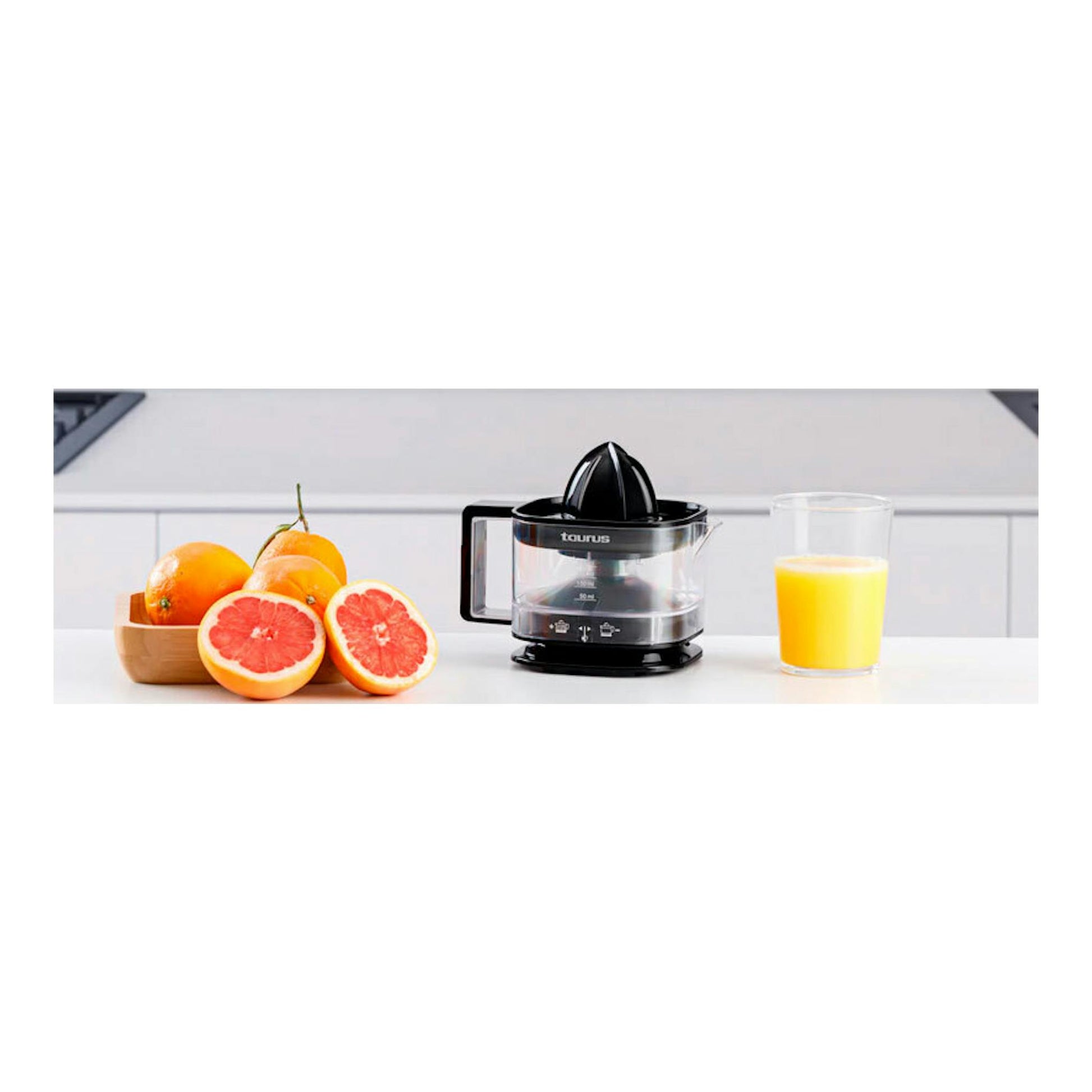 Exprimidor Taurus TC-350 Nero negro, vista frontal sobre encimera, junto a naranjas, pomelos y un vaso de zumo.