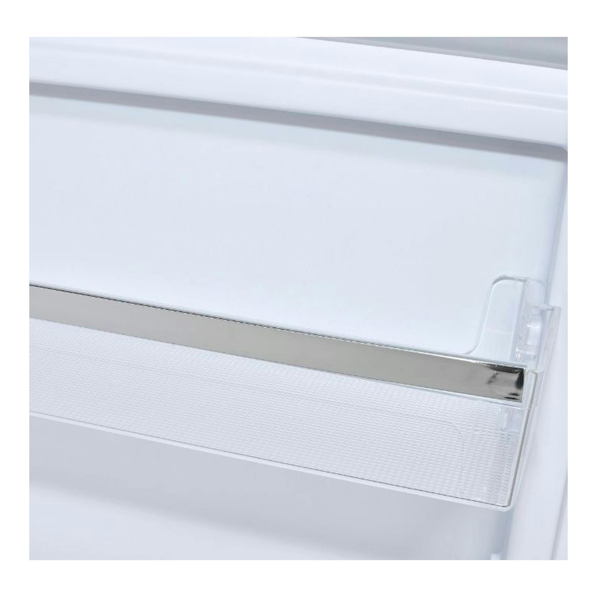 Primer plano del interior blanco de un frigorífico, con balda transparente y borde cromado.