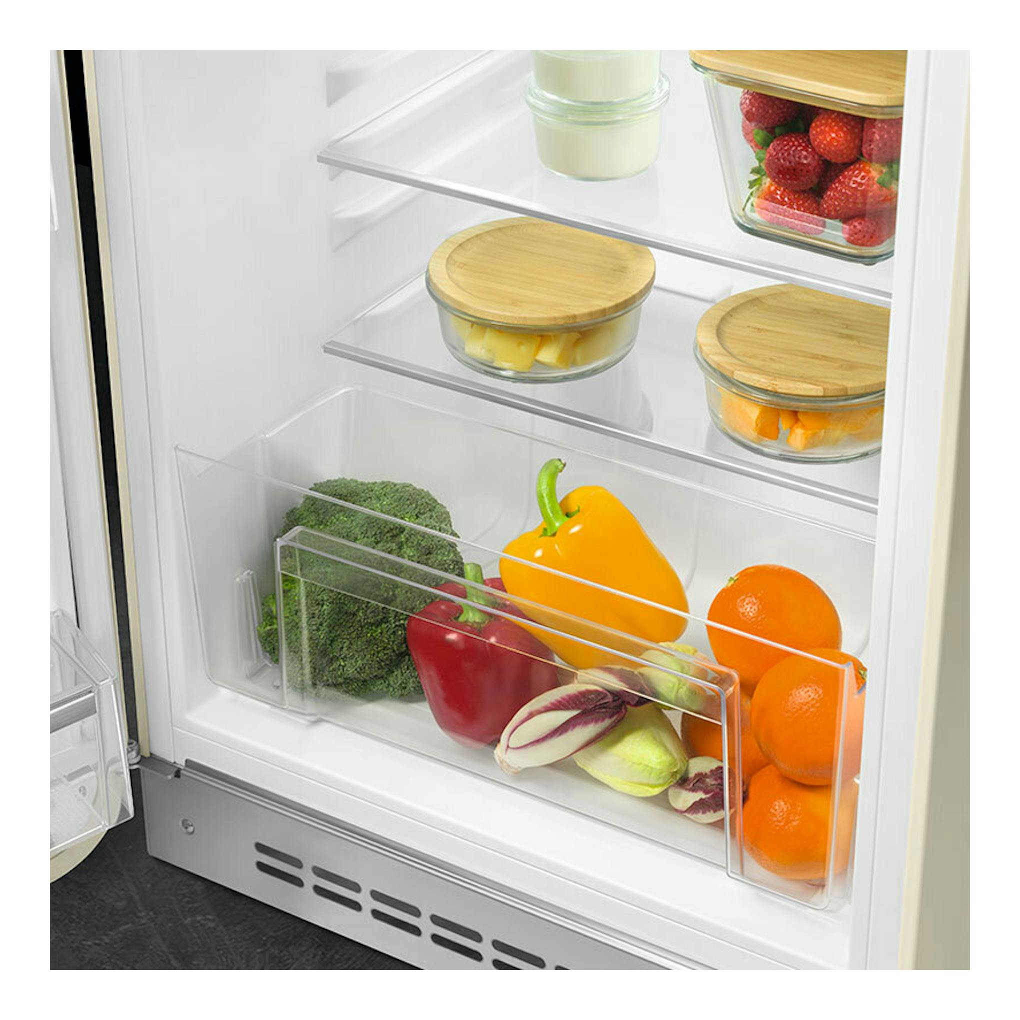 Interior del frigorífico Smeg FAB10LCR6 crema, vista frontal, con estantes de vidrio y verduras.