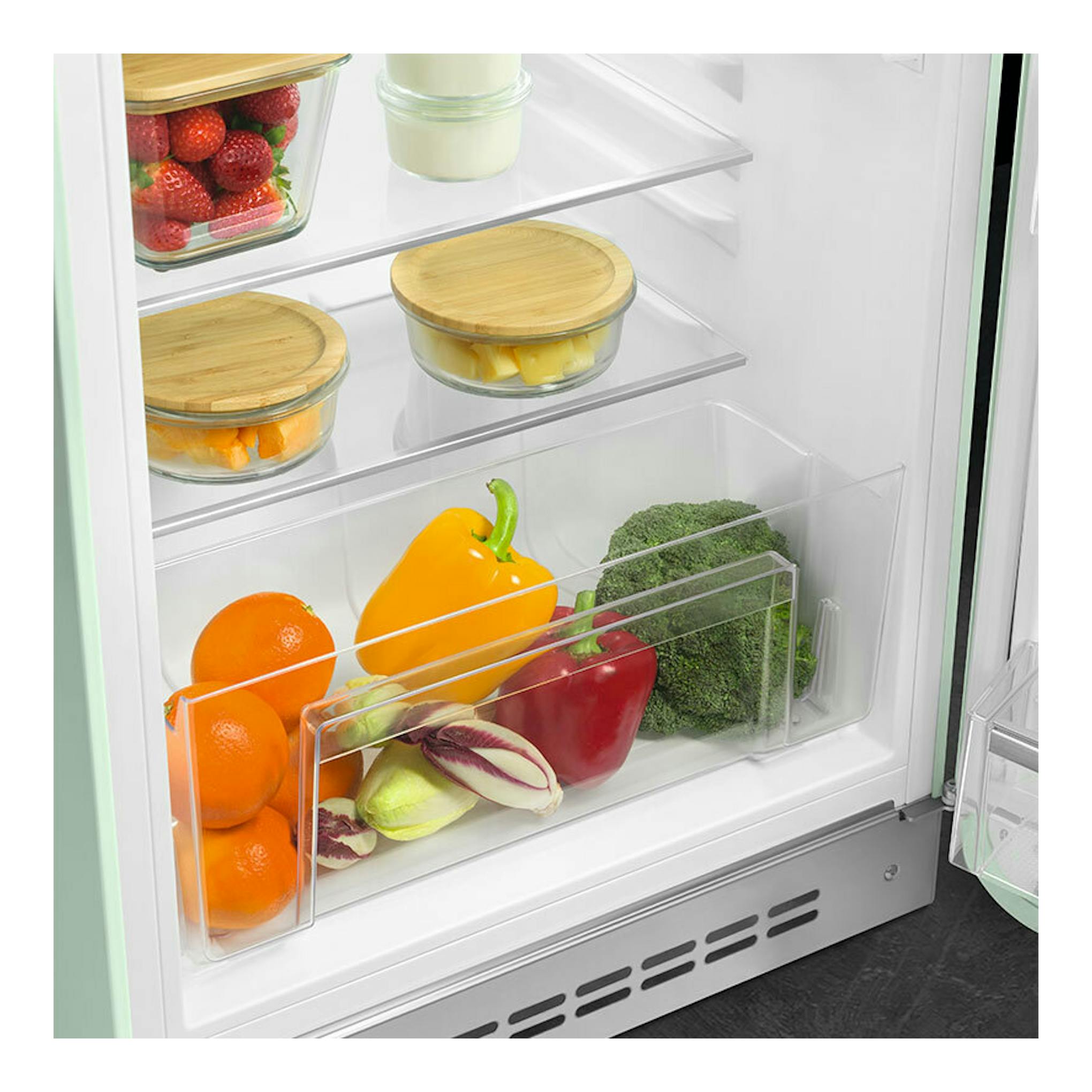 Vista interior frontal de frigorífico Smeg FAB10RPG6 verde agua con frutas y verduras en estantes y cajón.