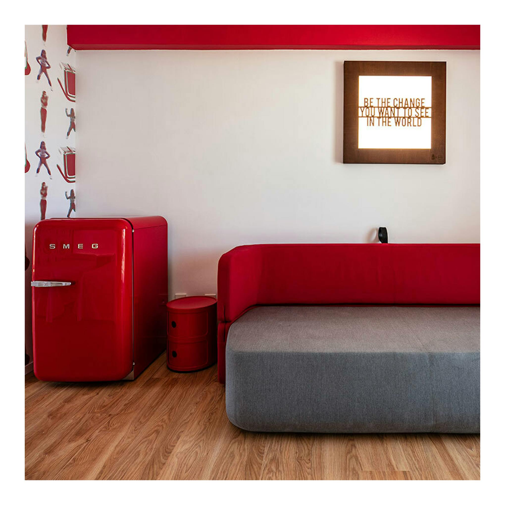 Frigorífico rojo Smeg FAB10RRD6, vista frontal, junto a una cama roja en una habitación.