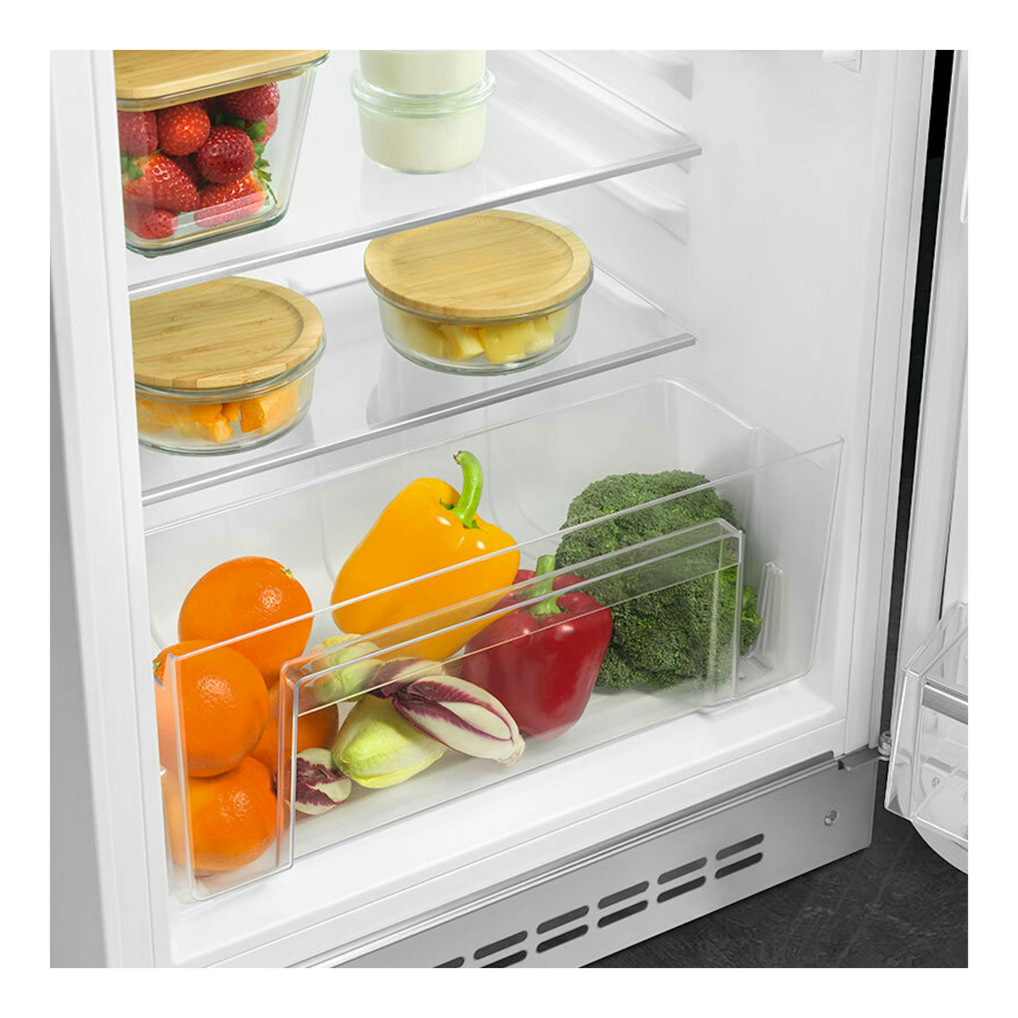 Vista interior frontal de frigorífico Smeg FAB10RWH6 blanco, con estantes de vidrio y verduras.