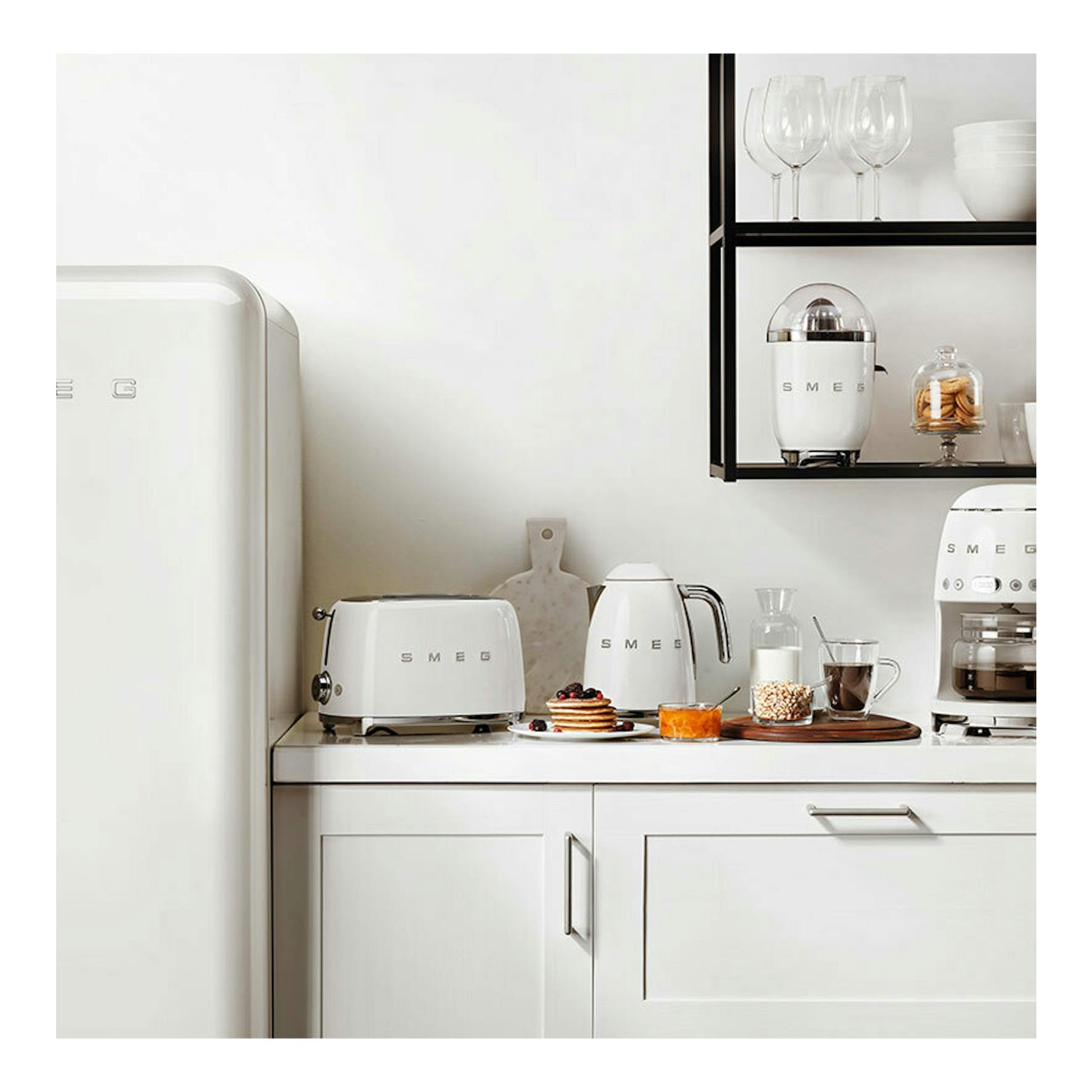 Frigorífico Smeg FAB28RWH6 blanco, vista frontal parcial, junto a una encimera con electrodomésticos blancos.