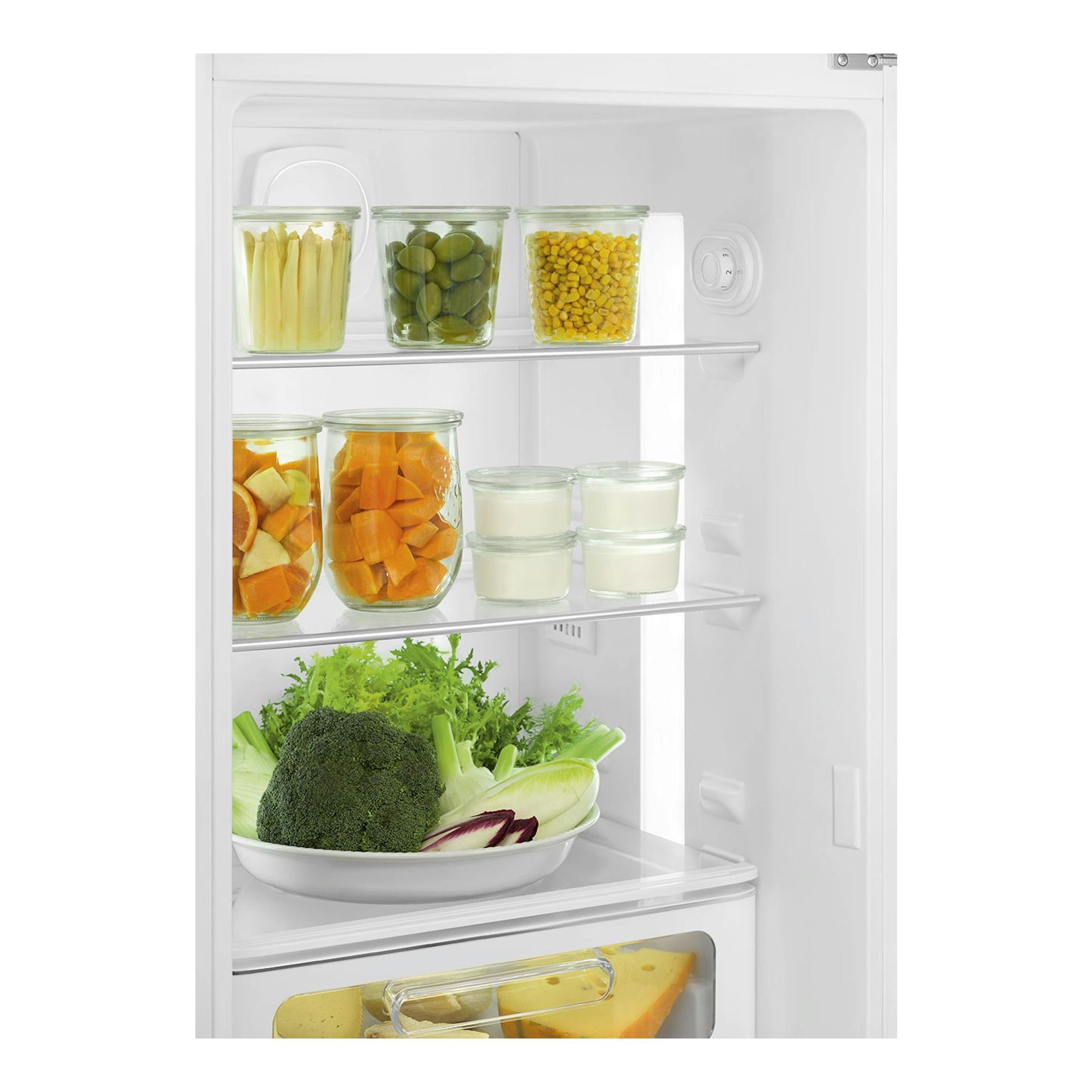 Interior frontal de frigorífico blanco con estantes, tarros con verduras y recipientes con yogur.