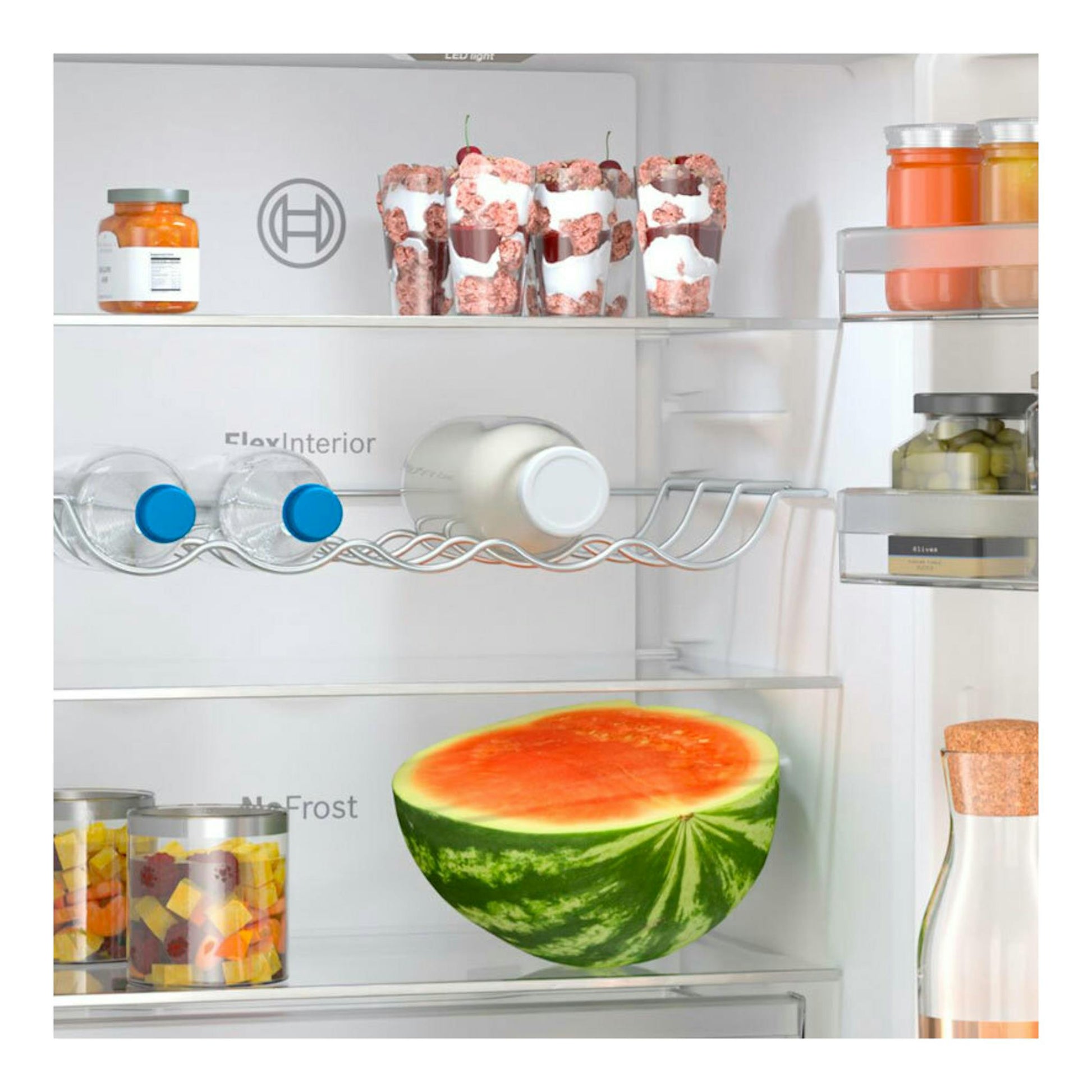 Vista frontal del interior de un frigorífico combi Bosch KGN36VIBT inox con botellas, tarros y medio melón.
