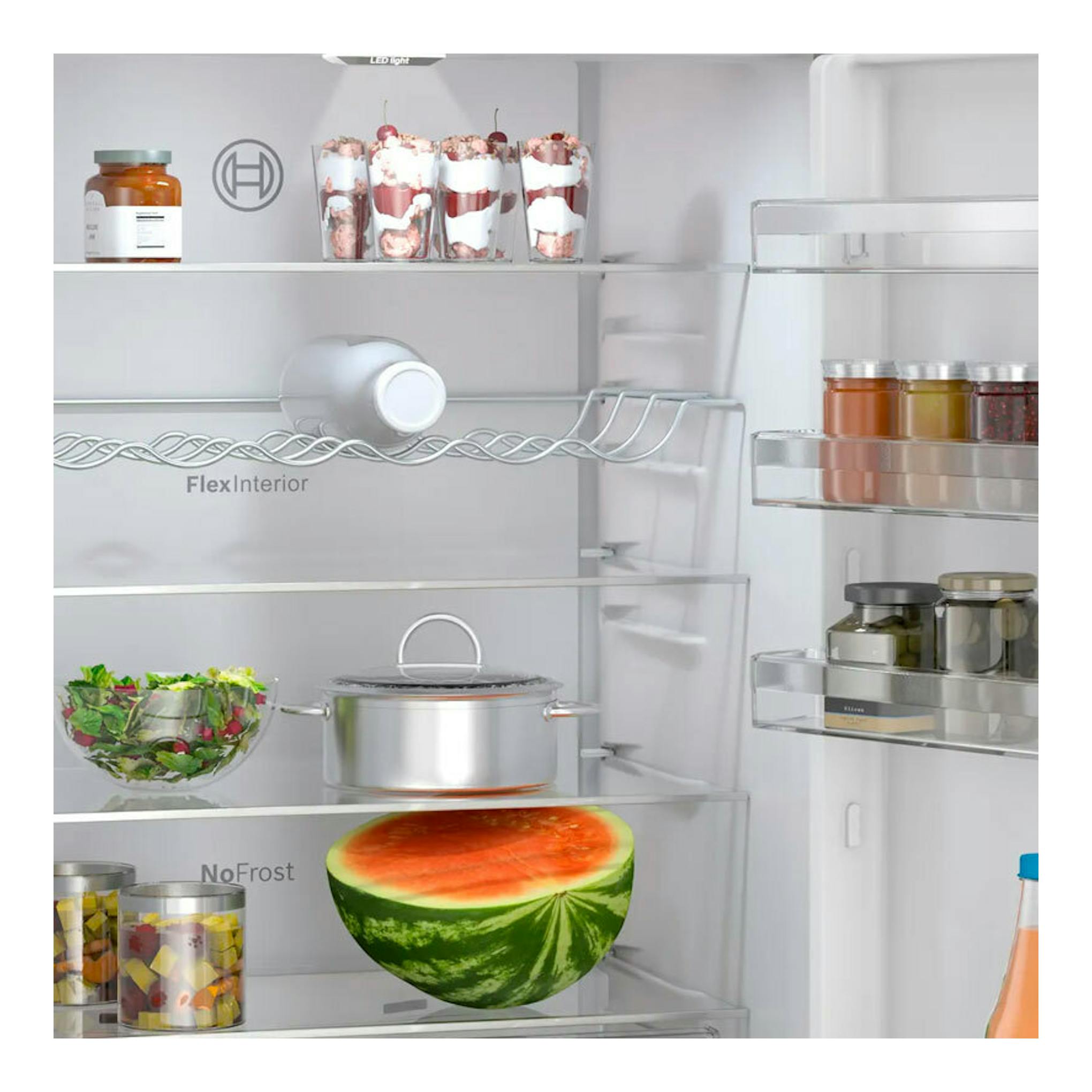Vista frontal del interior de un frigorífico Bosch KGN49OCAF Inox con estantes de cristal y alimentos.