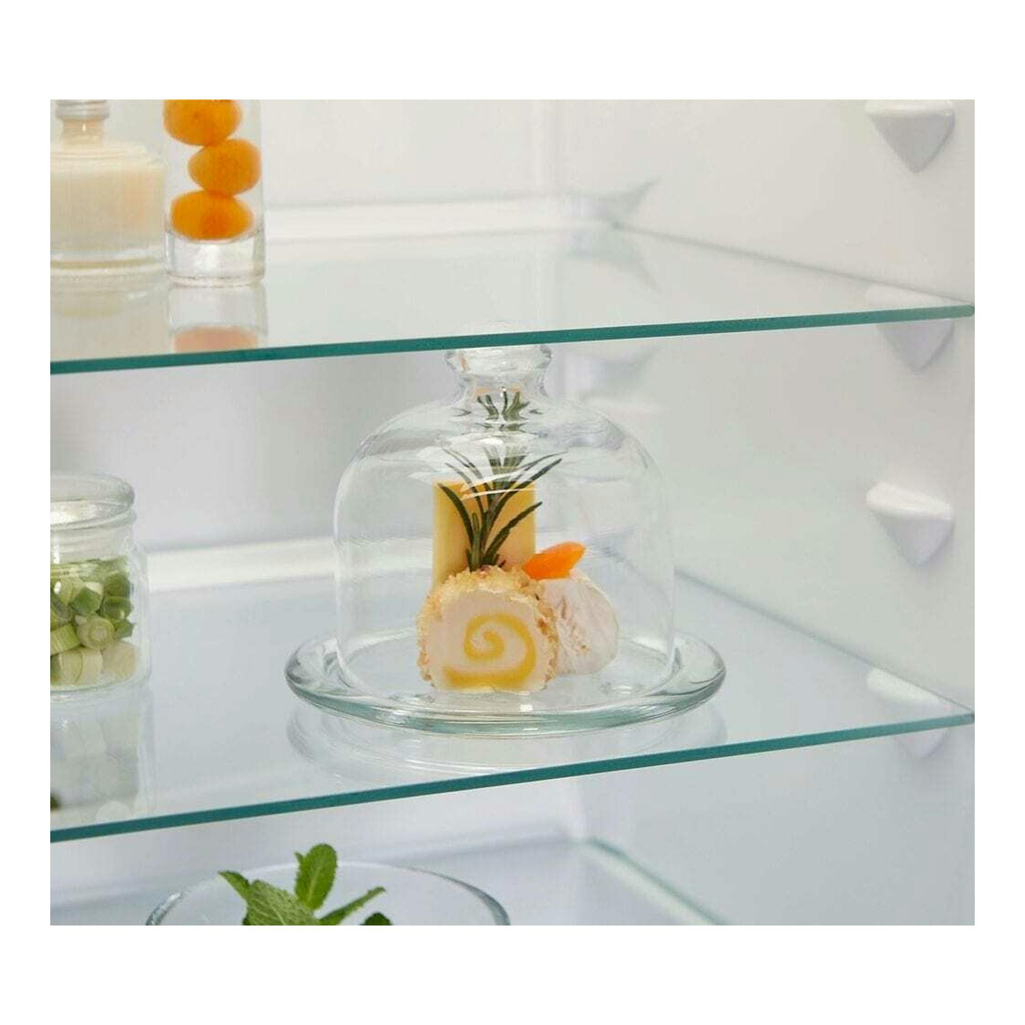 Interior de frigorífico combi blanco, con estantes de vidrio y postres en recipientes y tarros.