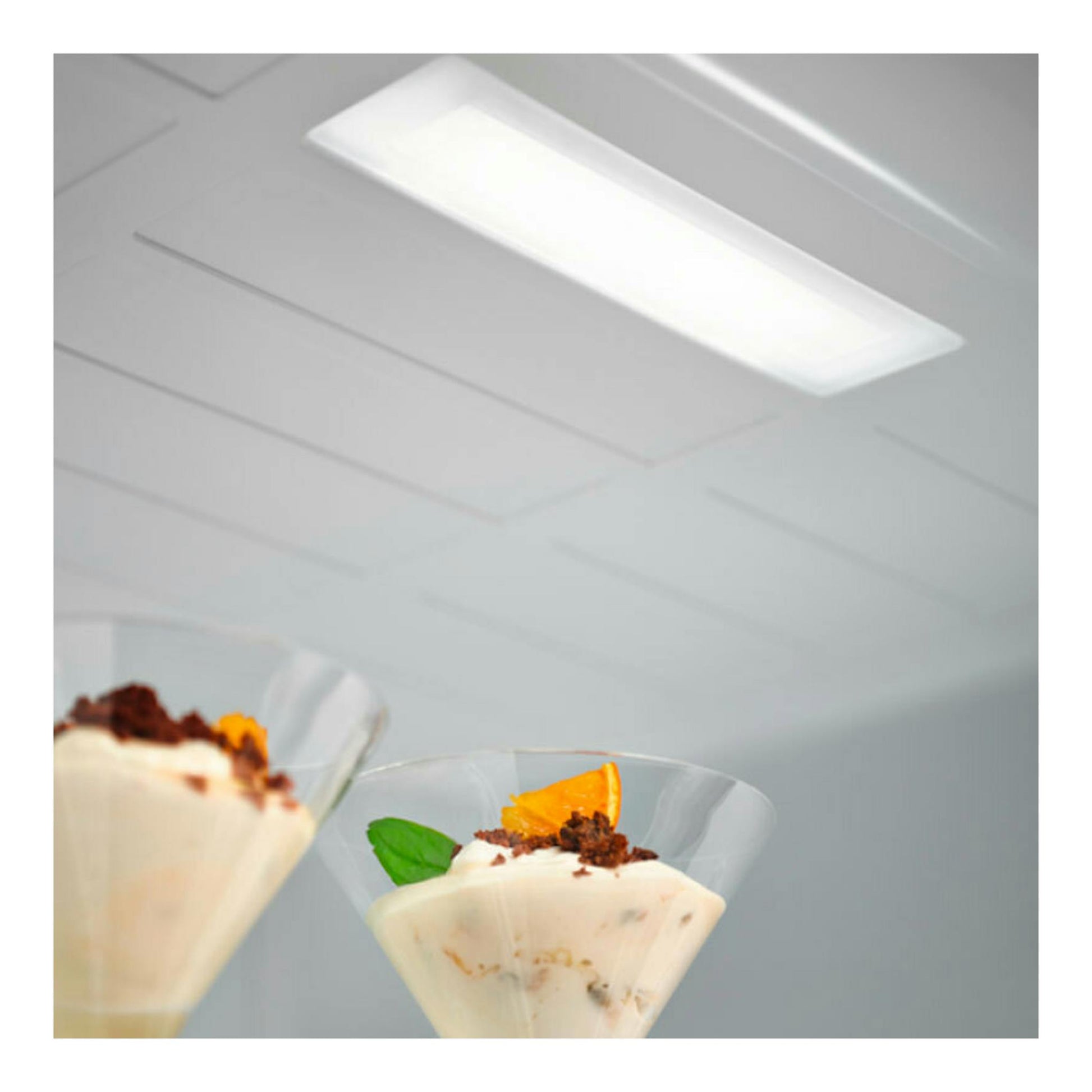 Interior de frigorífico Electrolux LNT5ME32W1 blanco, con copas de postre bajo luz interior.