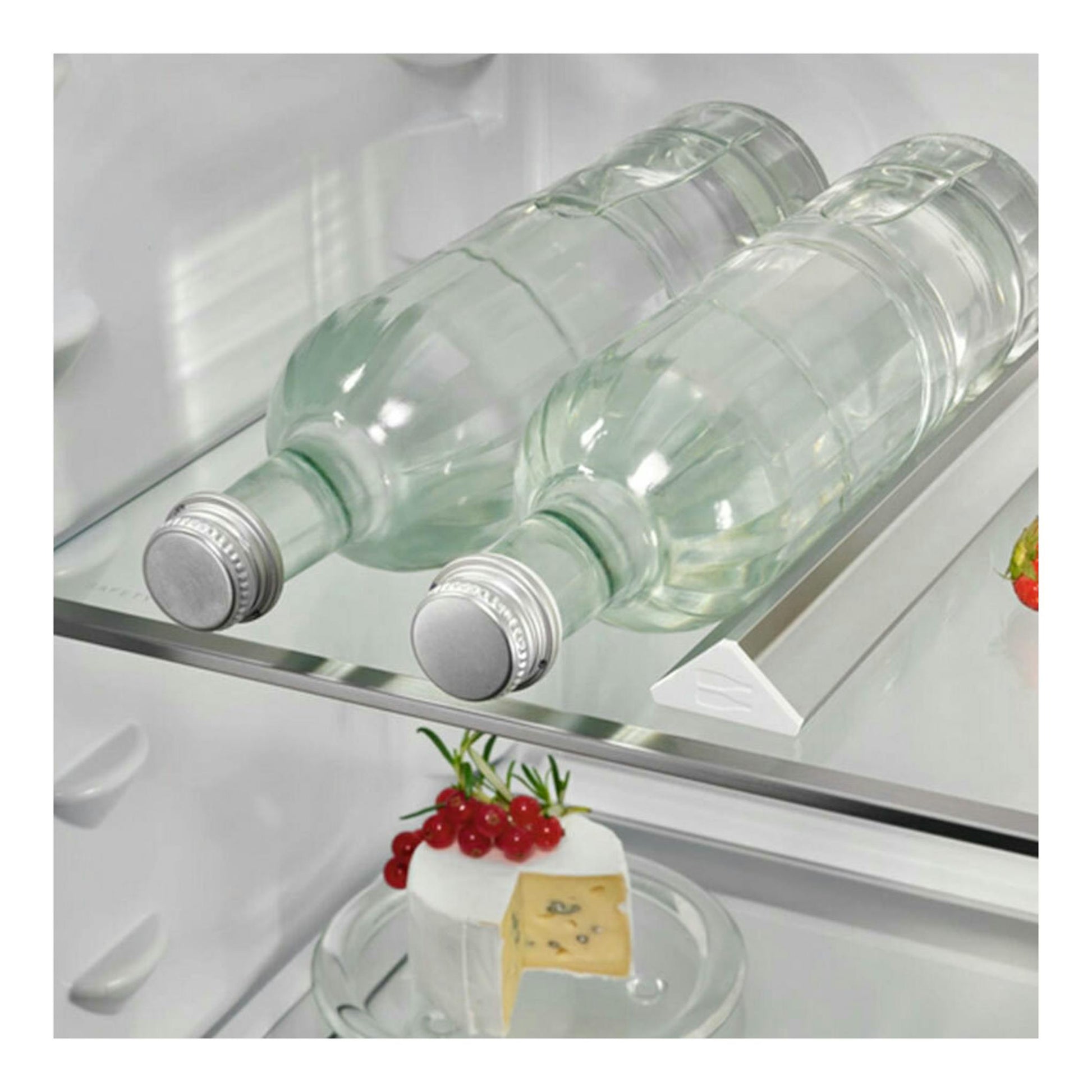 Interior de frigorífico combi integrable AEG NSC7P751ES, con dos botellas de vidrio y un postre en una balda.
