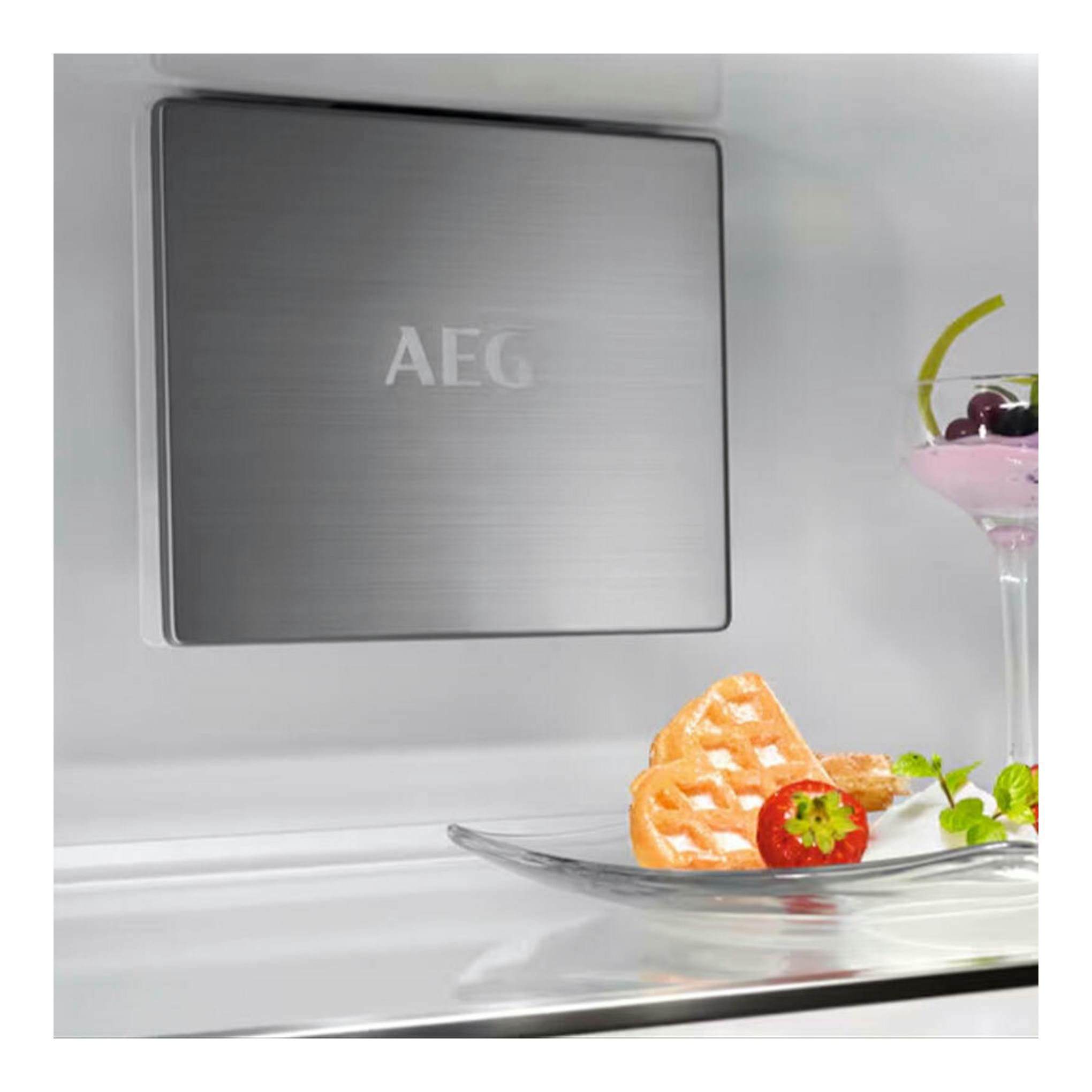 Interior de frigorífico integrable AEG NSC7P751ES, vista frontal del panel gris con logo AEG y estante de cristal.