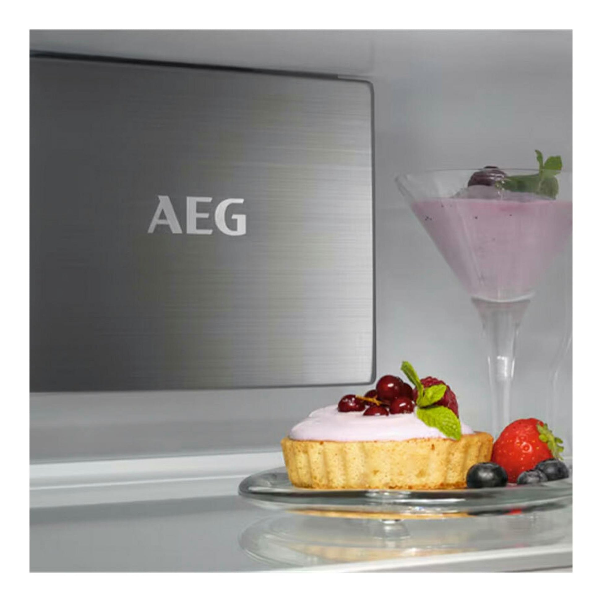 Frigorífico integrable AEG NSC7P751ES, vista frontal parcial en acero inoxidable con postre y copa en el interior.