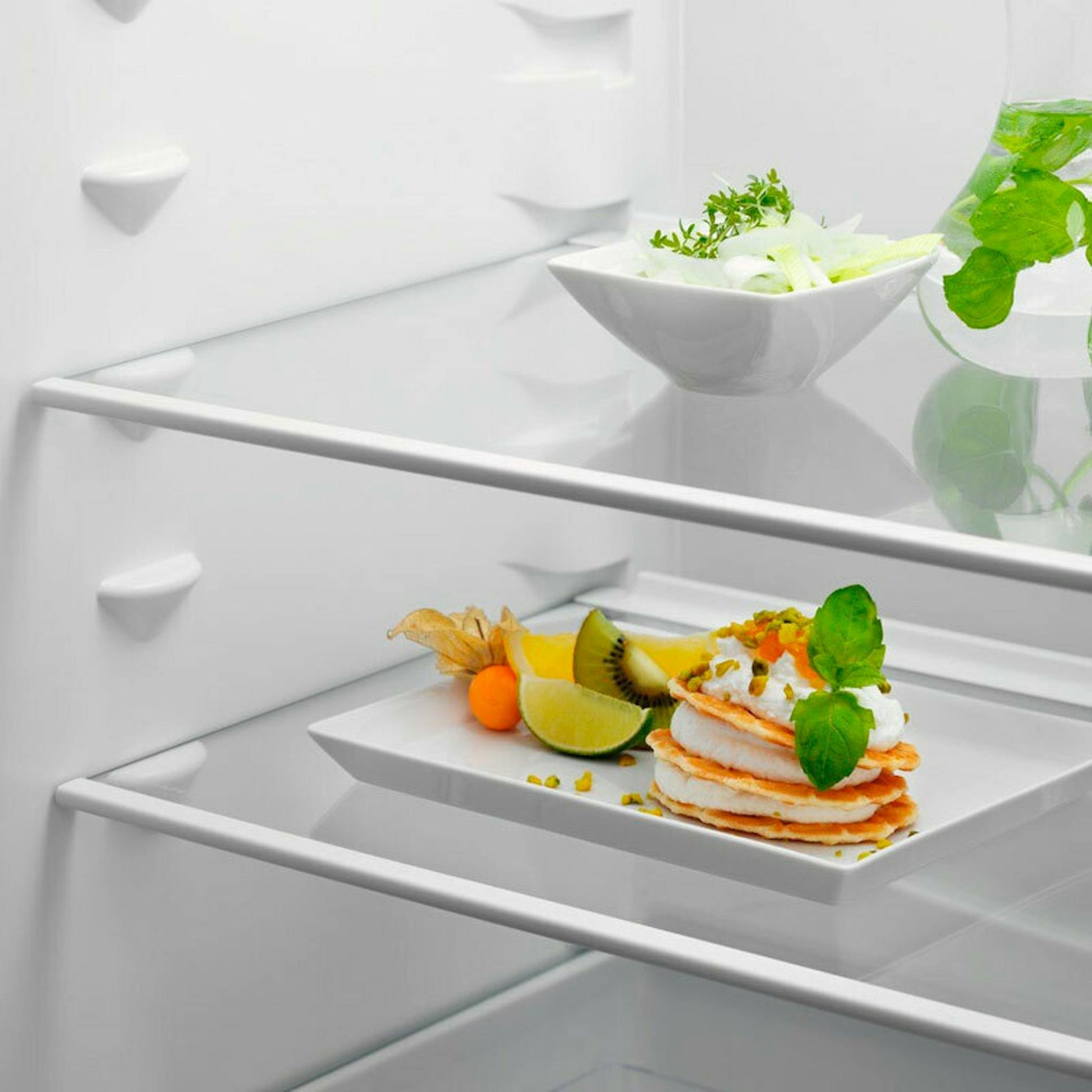 Interior del frigorífico combi integrable Electrolux ENT6NE18S con estantes de cristal y platos de comida