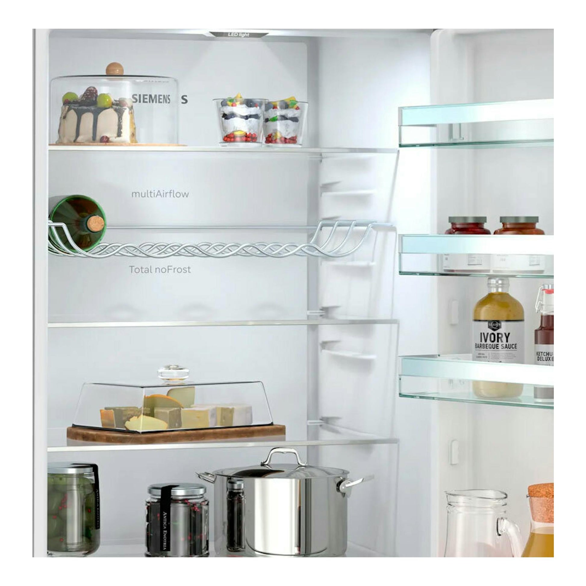 Interior de frigorífico combi Siemens KG39N2IAG inox, vista frontal abierta, con estantes de vidrio y alimentos.