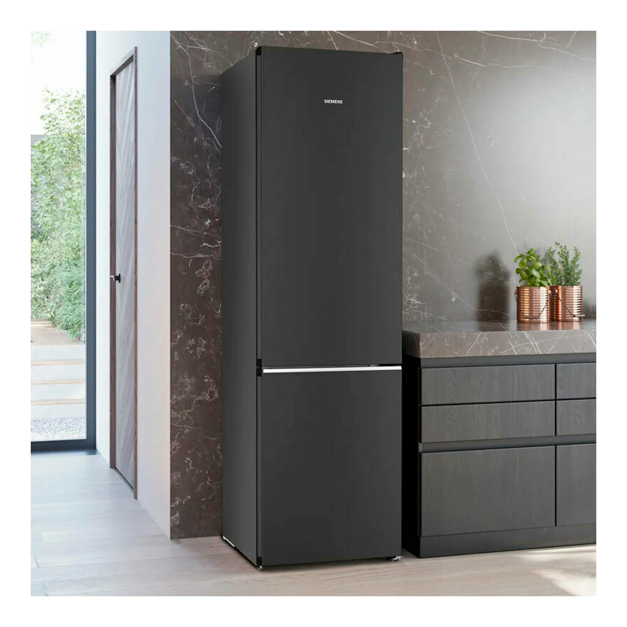 Frigorífico combi Siemens KG39N4X1F negro, vista frontal, junto a muebles de cocina en un interior moderno.