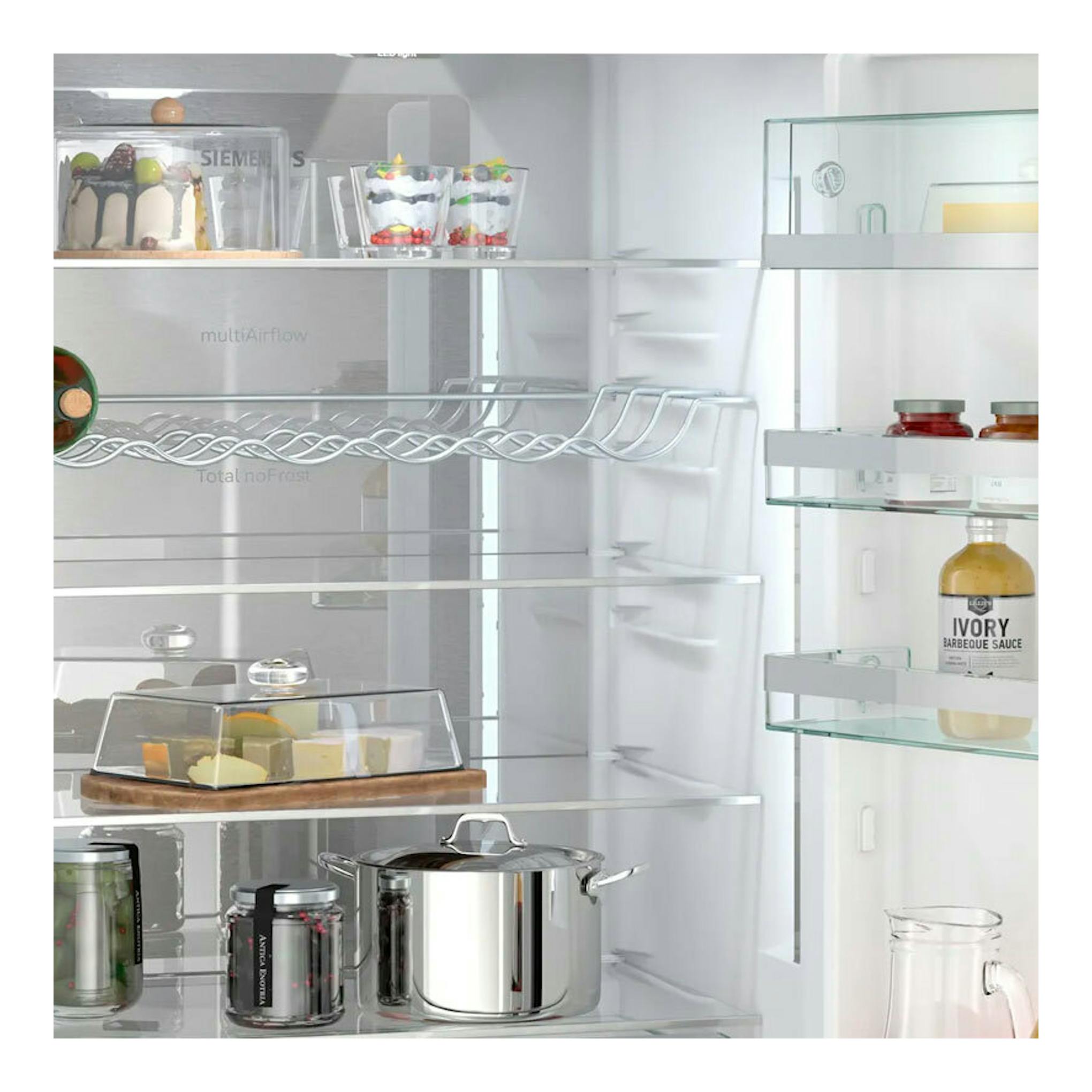 Interior de frigorífico combi Siemens KG49N4XAF en acero negro, con estantes de vidrio y alimentos.