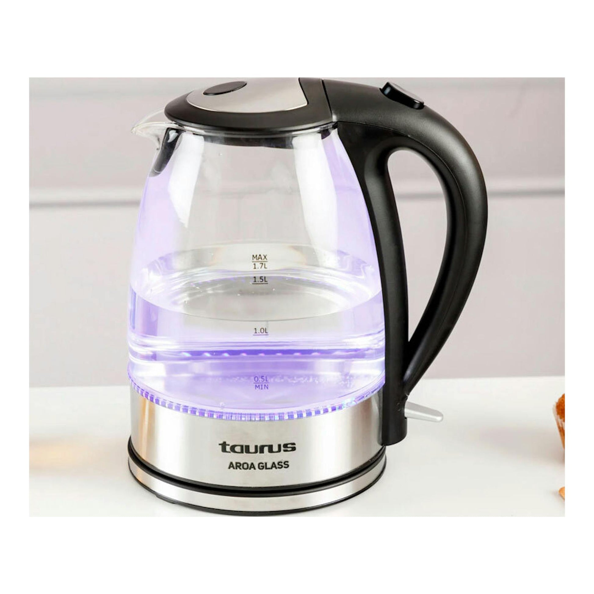 Hervidor eléctrico Taurus Aroa Glass de vidrio transparente, con asa negra y luz violeta, vista frontal lateral.