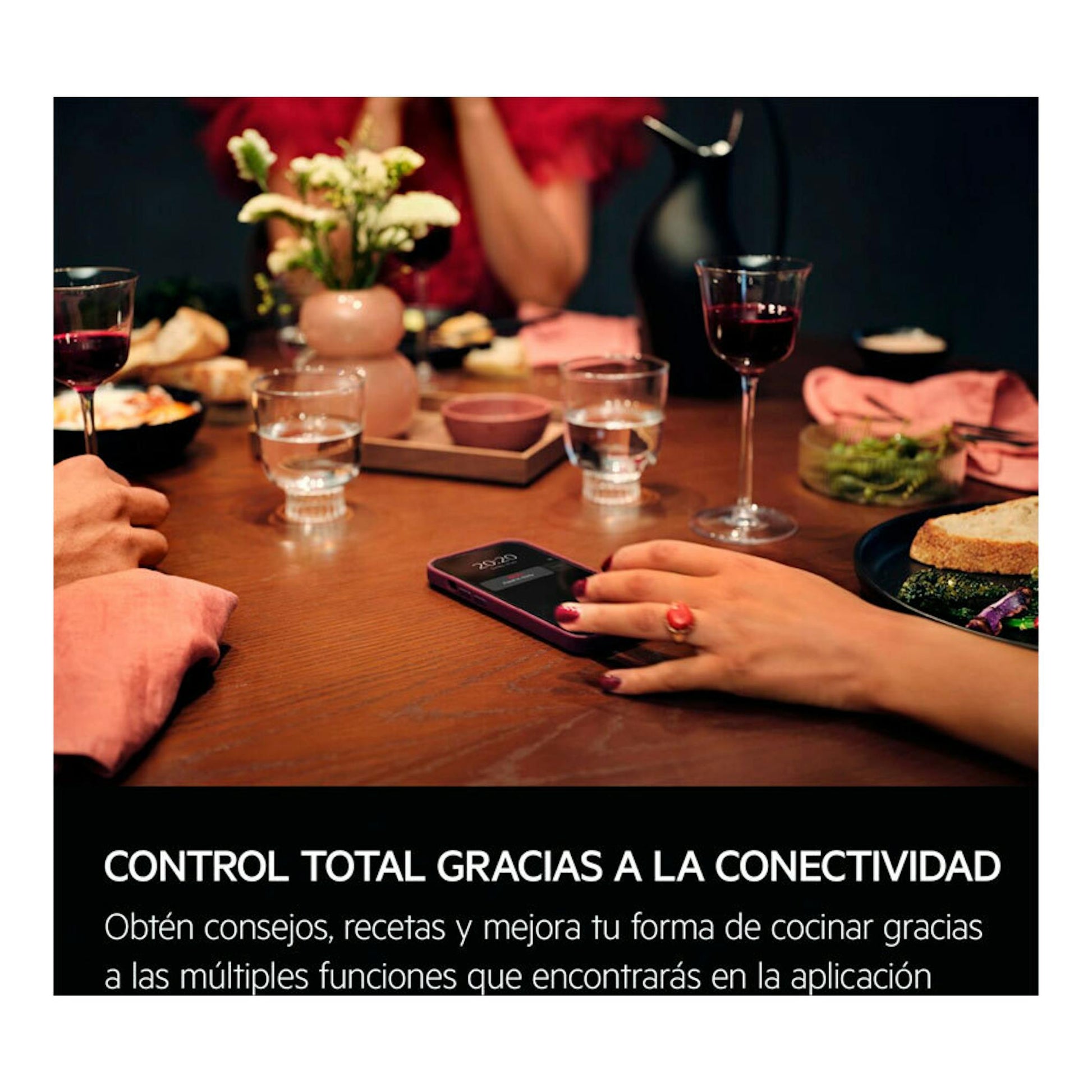 Mesa con cena y un móvil en primer plano; texto sobre conectividad de horno AEG OR6PB51WSB.