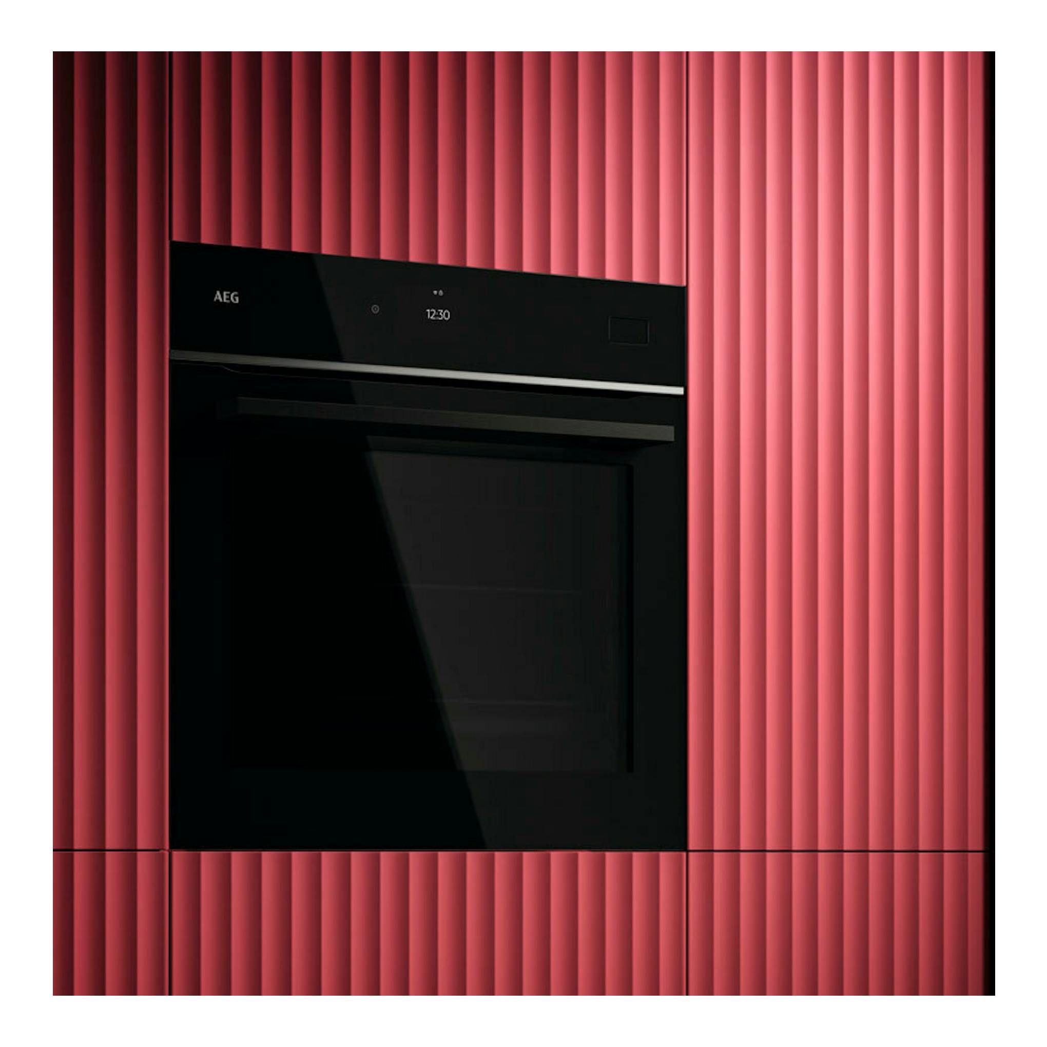 Horno empotrable AEG TB8SB73ZAB de cristal negro, vista frontal, integrado en pared roja acanalada.