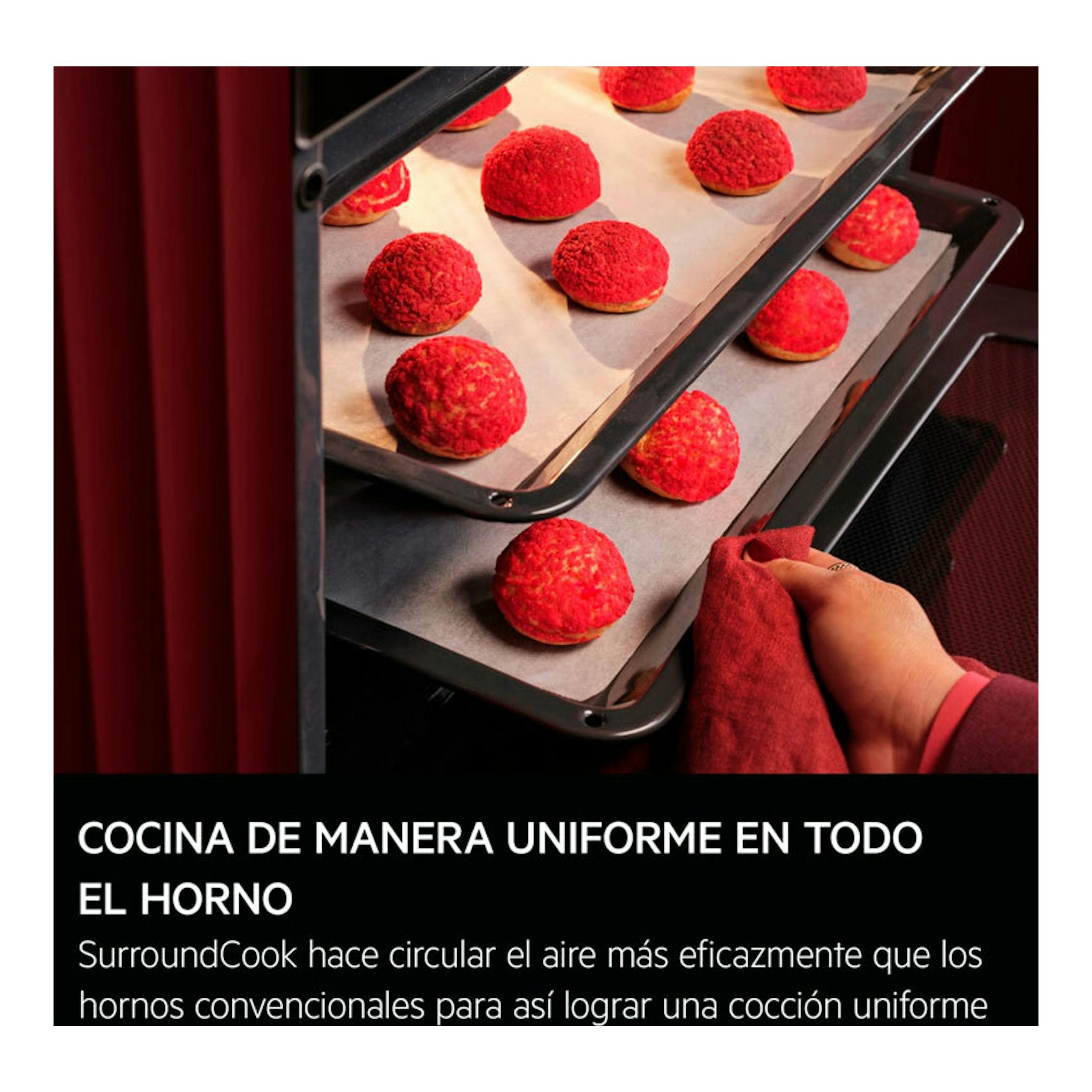 Interior de horno AEG TU5PB41FSK negro con bandejas de bollos rojos y una mano sacando una bandeja.