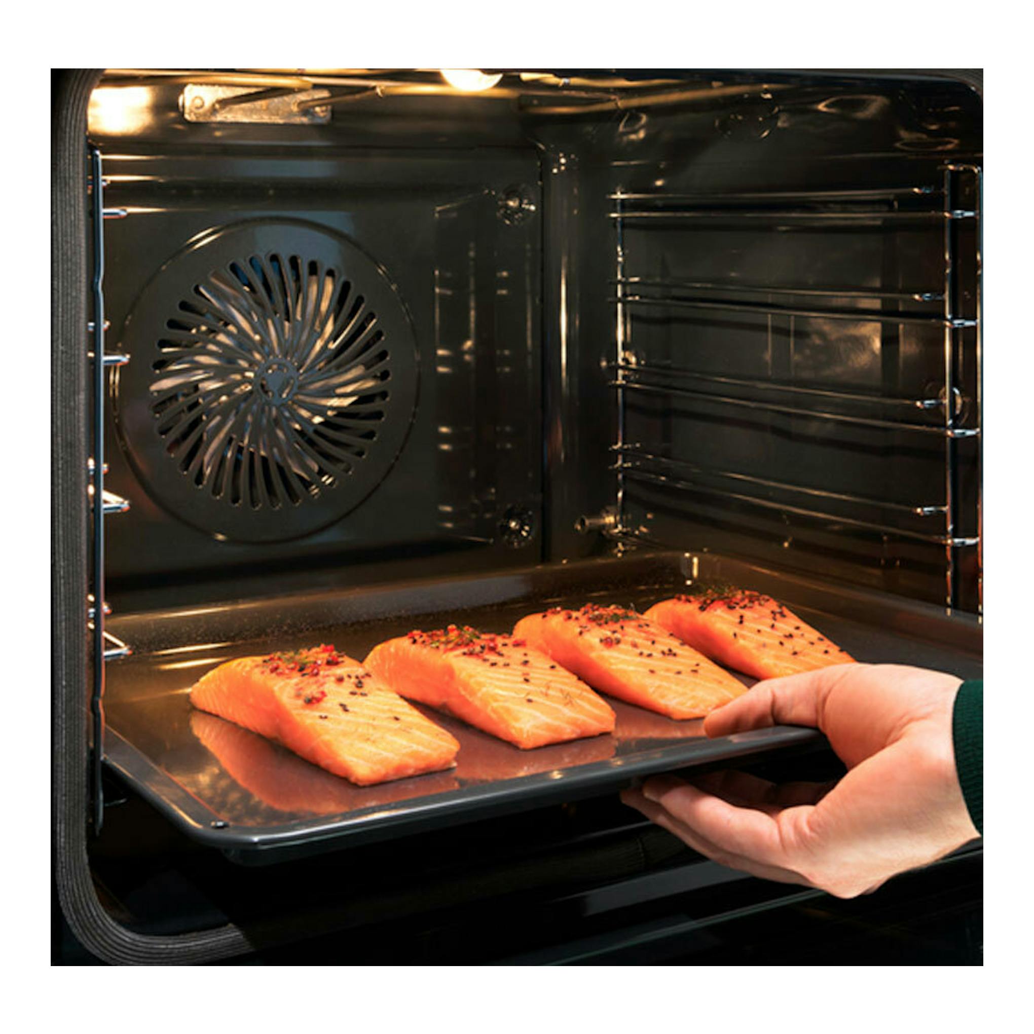 Interior de horno Electrolux EOB8S39X negro, con una mano colocando una bandeja con filetes de salmón.