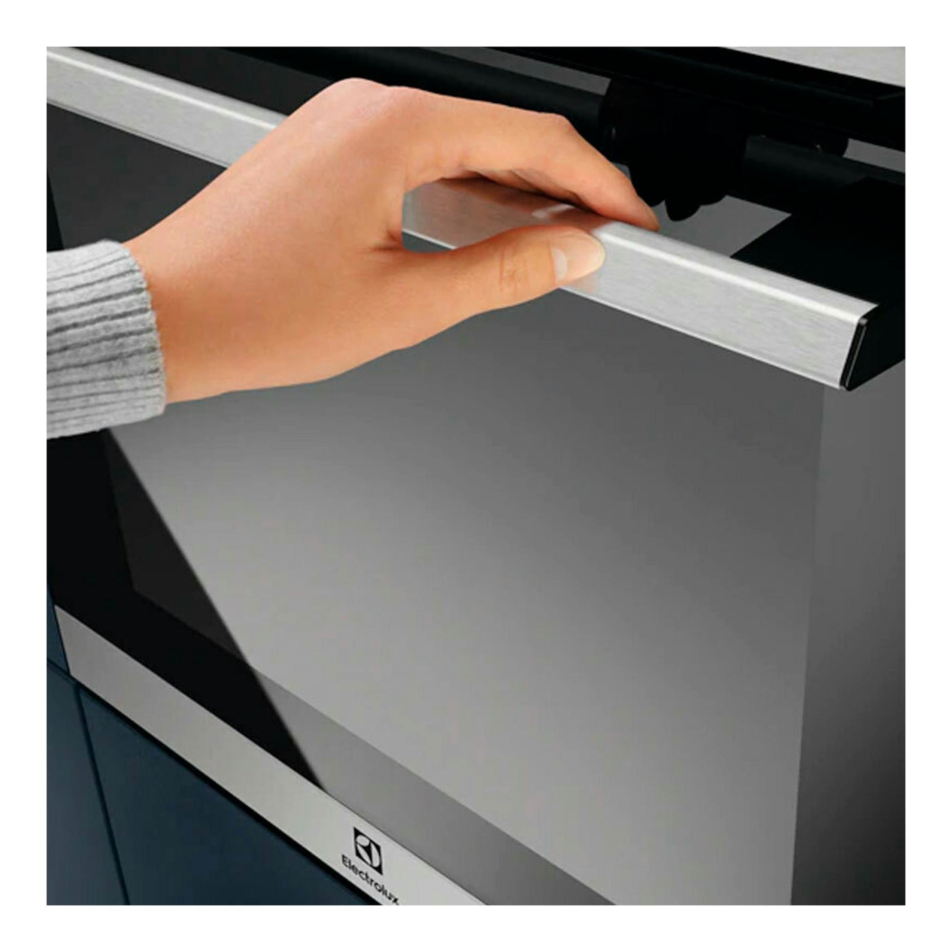 Horno Electrolux EOC6P77X inox, vista frontal, puerta de vidrio negro y tirador metálico, con una mano abriéndolo.